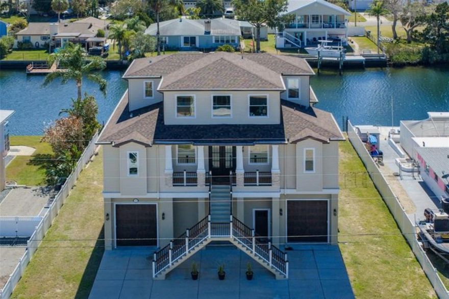 Welcome to this stunning custom waterfront residence with ELEVATOR offering 5 BEDROOMS + FLEX SPACE, 5 BATHROOMS, and a 4+ GARAGE on an oversized 9,400+ sq ft DIRECT GULF ACCESS lot with 84 ft of seawall in desirable Hernando Beach. With no HOA, no deed restrictions, and short-term rentals permitted, this exceptional property is ideal as a primary residence, vacation retreat, or income-producing investment.
Impressive curb appeal welcomes you with decorative concrete curbing, grand dual staircases, and a tiled front porch. Inside, the bright Great Room features 10 ft CEILINGS, a custom electric glass-front fireplace, and a pre-wired wine display area convertible to a wine cellar. The one-of-a-kind GOURMET KITCHEN offers TWO-TONED CABINETRY with DOUBLE CROWN MOULDING, quartzite countertops, FARMHOUSE SINK, and upgrades STAINLESS STEEL APPLIANCES. The oversized island includes built-in storage and seating, along with a convection oven/air fryer combo. A 6-burner gas cooktop with stainless hood, wraparound buffet with drawer microwave, custom live-edge coffee bar, and oversized walk-in pantry complete this chef’s kitchen. The adjacent dining area captures panoramic Gulf views.
QUADRUPLE SLIDERS open to a 22x15 covered lanai with decorative ceiling and half bath and  pre-plumbed for a future outdoor kitchen, complete with stainless hood. The waterfront primary suite features DUAL WALK-IN CLOSETS WITH CUSTOM SHELVING and a SPA-LIKE BATHROOM with floor-to-ceiling tiled shower, double quartz vanities, with built-in cosmetic and appliance drawers. The second level also includes a laundry room, half bath, and guest bedroom/office.
The third level offers three additional bedrooms plus a flex space, all with waterfront views. Two bedrooms share a JACK AND JILL BATH, while the fifth bedroom and flex space access a full bath with tub and shower combo. The first level provides parking for 4+ vehicles with 10 FT GARAGE DOORS and extensive storage. Outdoors, enjoy an epoxy-finished patio, covered pergola, 84 feet of concrete seawall, and floating dock w/ladder on a wide channel suitable for larg boats and sailboats.
Thoughtful upgrades include an EV CHARGING PORT, gas line for a future whole-home generator, pre-run gas and electric for a pool, electric for a future boat lift, exterior lift wiring to the third-level deck, and pre-plumbing for a future second-level pool and rear deck. Located minutes from Weeki Wachee Springs with easy access to Suncoast Parkway for commuting to Tampa, this golf-cart-friendly community offers boating, kayaking, paddleboarding, and fishing right from your backyard.
Coastal luxury, investment potential, and direct Gulf access—schedule your private showing today.