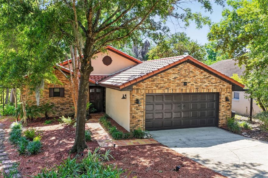 Welcome home to this hidden gem!  NO REAR NEIGHBORS!  CONSERVATION VIEW!  ENTICING CURB APPEAL!  This one-of-a-kind, stunning “Villa-style” residence is nestled on a cozy lot surrounded by mature trees providing a canopy of shade and serenity.  Located in a small community on a no thru traffic road offering a more private living environment.  Tastefully and lovingly updated over the years.  NEW TILE ROOF 2025 w/transferable warranty and 2023 Water Heater.  From the moment you enter, obvious pride of ownership reflects the thoughtful details, finishing touches and SPACIOUS DESIGN that sets the tone for comfortable, elegant living.  This 2 bed/ 2 bath boasts an OPEN CONCEPT split floor plan with 1,627 climate controlled sq ft, SOARING CEILINGS, a multitude of PLANTATION SHUTTERS, and complimented with copious custom SALTILLO TILE flooring throughout.  The rustic arched double door entry leads into a quaint foyer where you immediately see VAULTED CEILINGS and beautiful crown molding.  The Dining Room connects to the EXPANSIVE 15x25 Living Room which includes a wood accent hearth/mantel, wall mounted TV, and an electric fireplace.  This versatile design flows seamlessly and lends itself perfectly for all those family holiday gatherings.  The TRIPLE SLIDERS invite you onto the 22x30 SCREENED LANAI with PANORAMIC VIEWS, perfect for entertaining.  Enjoy sipping your wine or simply wind down the day in your Florida green space while you chillax.  The generous Primary Ensuite has access to the Lanai, a decorative vintage fireplace façade, WALK-IN CLOSET & a meticulously updated bath w/shower stall + beautiful CUSTOM FARM DOOR.  The chef friendly galley kitchen has a small coffee nook, abundant cabinetry, French Door access to the Lanai, and close to the INSIDE LAUNDRY.  The guest room could double as an office with a convenient alcove adjacent to the closet, and nearby is the second updated bath w/magnificent refinements.  The Woodlands has its own community dock plus the monthly HOA includes lawn care.  Location benefits include shopping, restaurants, Hospital, access to toll 429, Theme Parks, both historic downtown Mount Dora and Eustis First-Friday events.  Daytona Beach is about 90 minutes.  Make this lovely home your next address.