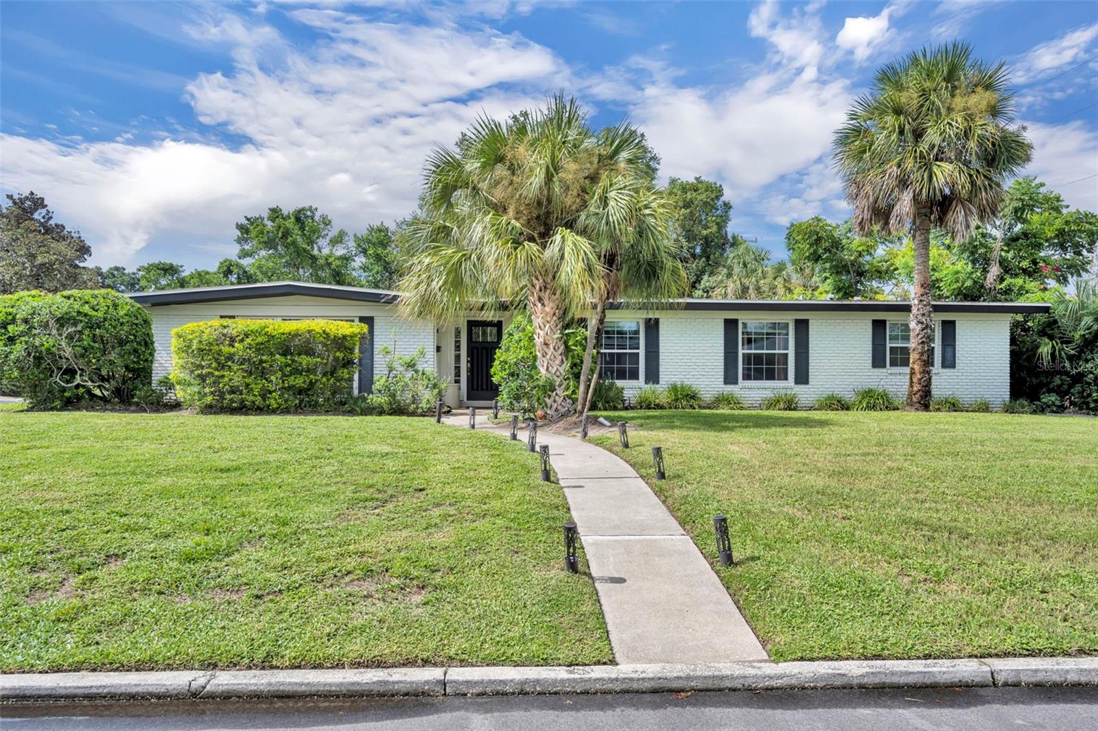 Situated on a lush corner lot in the highly sought-after Dommerich neighborhood, this spacious pool home welcomes you with an open foyer and bamboo flooring throughout the formal living areas. To the left, a large formal living room with exposed beams and large windows flows into the dining room, which leads through a doorway to the kitchen. Or, head straight from the foyer into the expansive eat-in kitchen featuring white cabinetry, stone countertops, stainless steel appliances, and a striking island topped with reclaimed Southern oak pine sourced from a vintage bowling alley. The kitchen opens to a breakfast nook and family room with tile flooring, a half bath, French doors to the backyard, and abundant natural light. Down the hall, two generously sized bedrooms feature wood-look tile, and a third bedroom—currently used as an office—offers a walk-in closet and glass doors to the family room. The oversized primary suite, rare for this neighborhood, includes backyard access, a huge walk-in closet, and a spa-style bathroom with double vanities, soaking tub, and large walk-in shower. Outside, the fenced yard is private and lush with mature landscaping, a pool, and a pavered patio. The home was renovated in 2014 down to the studs, including new windows, bamboo flooring in the formal areas, roof, electrical, and plumbing. The AC was replaced in 2020. Located within the neighborhood and zoned for top-rated schools—Dommerich Elementary, Maitland Middle, and Winter Park High—this home offers the convenience of walking or biking to school, and a short drive to downtown Winter Park as well as easy access to all that Maitland has to offer.