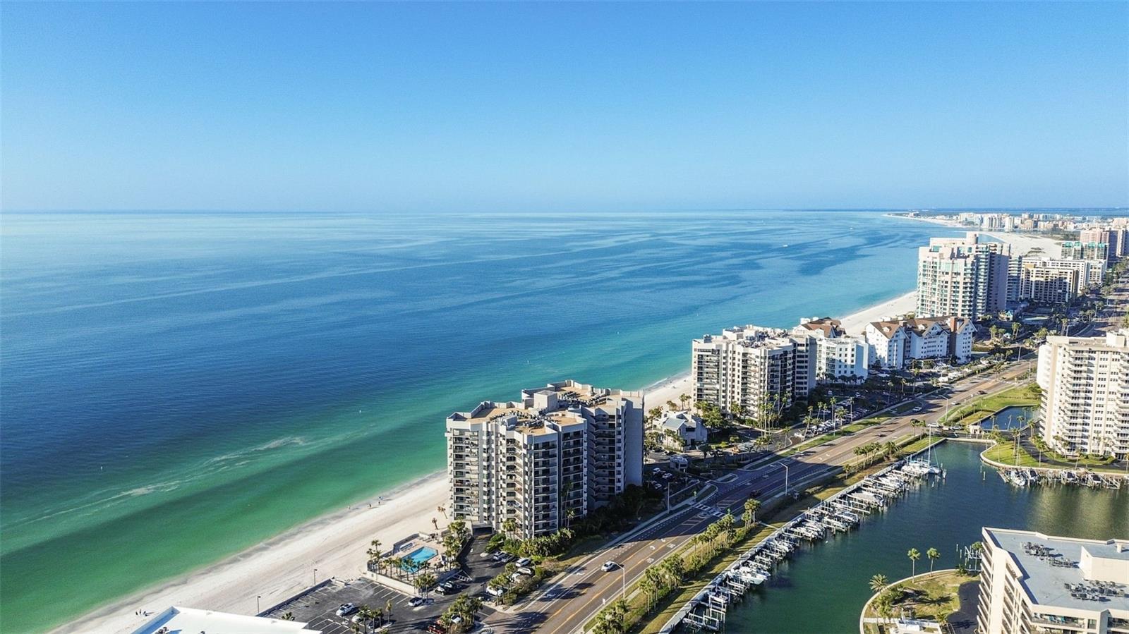 Experience refined Gulf-front living at the prestigious Dan’s Island Condominiums on Sand Key Beach in Clearwater. This premier beachfront residence offers breathtaking, unobstructed views of the Gulf of Mexico from every room and a sweeping 56-foot wraparound balcony that seamlessly blends indoor and outdoor living. Enjoy the gentle sound of waves just beyond your doorstep, a constant reminder of the tranquility of coastal living. This 2-bedroom, 2-bath, 1,610 SF residence features over $100,000 in PGT hurricane-impact sliding doors and windows, updated flooring throughout, new LED lighting, fresh professional paint, and a sleek electric fireplace that adds warmth and style to the spacious great room. The open-concept layout includes Gulf-front dining, a sun-filled living area, and a primary suite with wraparound balcony access, a generous walk-in closet, and a spa-style bath. The guest suite also offers stunning Gulf views, a private balcony, and a walk-in closet. Additional highlights include a large in-unit laundry room and ample storage. Dan’s Island is exceptionally managed and maintained, with on site office, offering residents an array of resort-style amenities, including 24-hour gated security with guard, a heated pool and spa, outdoor gas grills, recycling services, double elevators, a well-equipped fitness center, indoor basketball and racquetball court, and a two-story clubhouse with kitchen, billiards, wet bar, and outdoor terraces—creating the perfect setting for elegant coastal living.