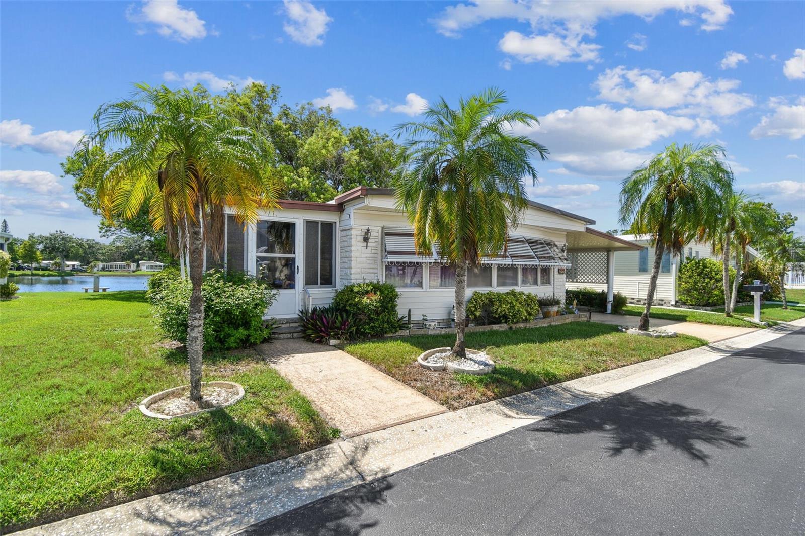 RARE Lakefront Double Wide in Highly Sought after Glenwood Estates. This Hidden Gem -Age qualified Park is one of the few Resident-Owned Communities where you OWN the land! Enjoy waterfront living in this spacious lakefront double wide home perfectly designed for comfort and convenience. Featuring 2 large bedrooms, each with walk-in closets and 2 bathrooms, this home offers plenty of room for relaxation and storage.
Interior: The primary bedroom overlooks the lake and boasts an ensuite bathroom with a shower and seperate vanity area as well as a large walk-in closet, creating a true private retreat. The Guest Bedroom suite also has a walk in closet and built in Desk and storage area. The bright, light-filled Florida room provides the perfect space to take in the serene views, while the pass-through kitchen makes entertaining easy and connects seamlessly to the dining room, complete with built-in shelves and additional storage. This home comes Furnished for an easy transition to your next Florida home.
Exterior: Situated on a generously sized lot with open green space around it, your are immediately drawn to the Deck overlooking the Lake creating a serene space to enjoy your morning coffee or a great book. Outside, the large 35 ft. carport accommodating two cars and a golf cart, and the oversized lot that gives you extra privacy and space. Just steps from the pool, this home is ideal for enjoying the Florida lifestyle year-round..Glenwood Estates is one of the few resident-owned manufactured home communities where buyers can obtain traditional financing—you own the land outright?. The community offers a heated pool, lakeside shuffleboard courts, a fishing dock, and a clubhouse with billiards, a library, and a full calendar of social activities. The low $320/month HOA covers internet, cable, water/sewer, lawn care, and trash pickup.
Located just 3.5 miles from Our Award Winning Beaches and close to shopping, dining, several golf courses, and both Clearwater-St. Pete and Tampa International Airports, Glenwood Estates delivers the Florida lifestyle you’ve been searching for—with financing available, no Flood Zone, and Pet Friendly. These Lakefront units are rare so call today for your private showing.