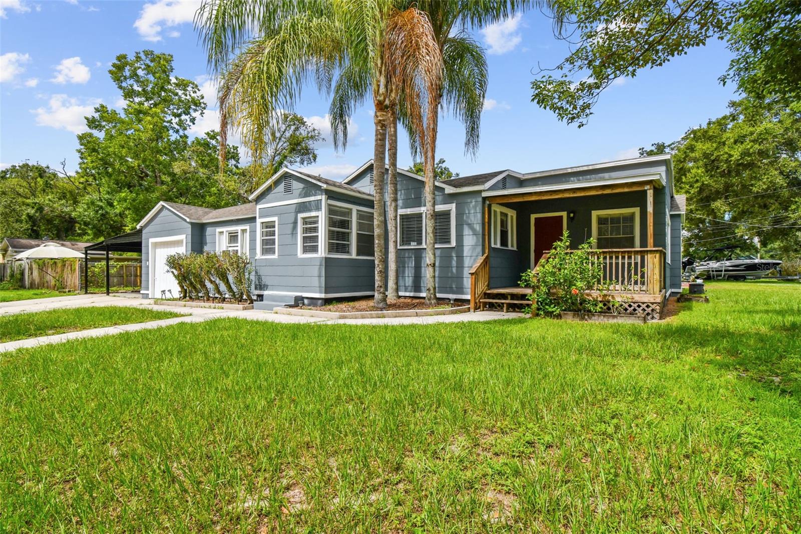This beautifully updated 3-bedroom, 2-bath home sits proudly on a spacious corner lot in sought-after Old Seminole Heights, offering the perfect blend of modern upgrades and timeless bungalow character. Freshly painted inside and out in 2025, the home welcomes you with bright, open living spaces, a functional floor plan, and thoughtful details throughout. Inside, original hardwood floors flow through the main living areas, preserving the home’s historic warmth, while wet areas are finished in stylish ceramic tile. The open kitchen features on-trend light wood cabinetry, dark granite countertops, and stainless steel appliances. A large family room with abundant windows fills the space with natural light, while two additional versatile area can serve as a formal dining room, living room, or office to suit your lifestyle. Off of the kitchen is an additional space perfect to use as a large panty or mudroom leading to the laundry room and attached 1 car garage. The separate floor plan allows for a private primary suite that boasts a remodeled master bath with a walk-in shower, new vanity and tile. The other 2 guest rooms share a full bathroom with an updated tile, vanity, and tub. In 2025, the attached one-car garage was enhanced with new drywall and recessed lighting for a more finished feel, complementing the two-car carport that provides ample parking and storage. Step through French doors to a private, custom wood deck ideal for year-round enjoyment. The fenced yard offers beautiful mature trees in both the front and back. Walk to local parks and dining, with SoHo and Downtown just minutes away — this is the perfect location to enjoy the best of Tampa living.