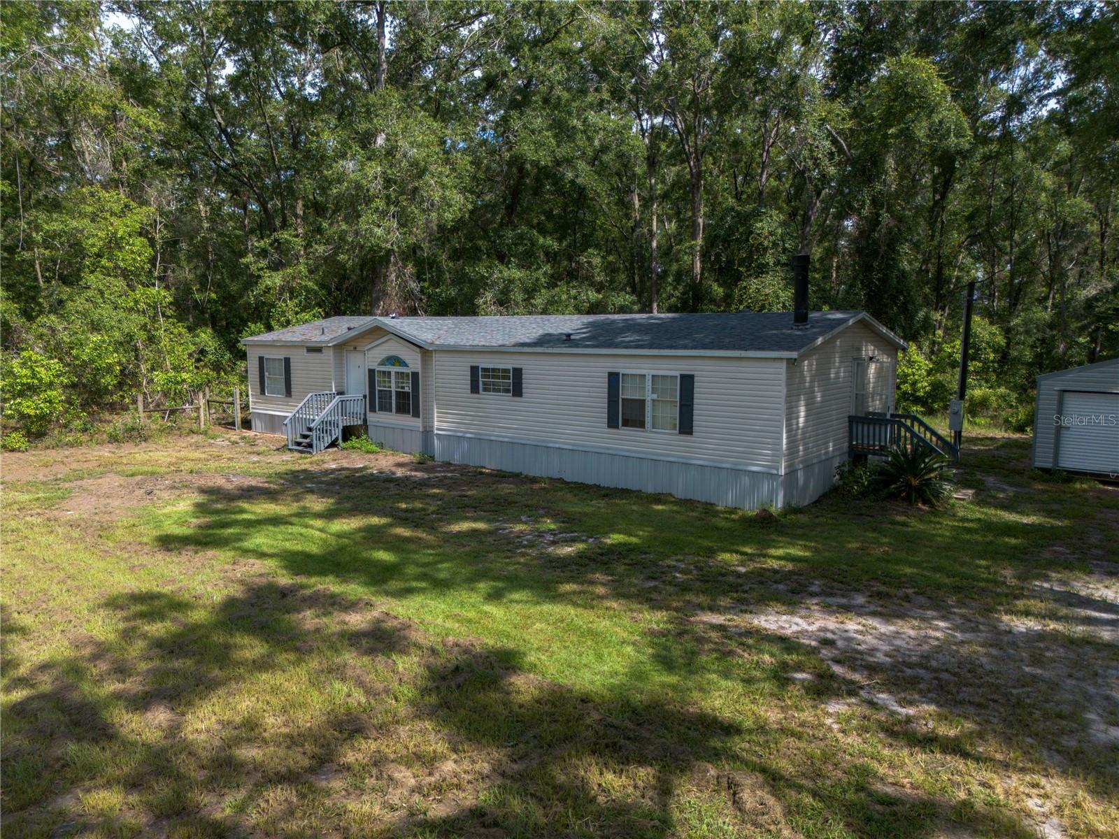 Set back in a private, wooded lot, this three bedroom two bath home sits on just over 5 acres. It has an amazing location being only 4 minutes from downtown High Springs which means you are only a short distance from shopping, restaurants, and many natural springs (Poe, Blue, and Ginnie Springs) which are true hidden gems of North Florida! The property improvements on this 1995 double-wide will allow you to enjoy peace of mind knowing that the roof (2023), water heater (2025), plumbing piping (2025), and HVAC (2024) are all newer! The home is located off of a city-maintained, paved road at the end of the neighborhood with no outlet road, so peace & quiet that come from no thru traffic are definitely perks you will enjoy here! You will also appreciate the added storage from the new 12x24 metal outbuilding with custom metal shelving on the property. You will find many beautiful trees on this high and dry property and the area is teeming with wildlife...deer and turkey are just a few things found in abundance. With a little TLC, you could make this rural retreat your own!