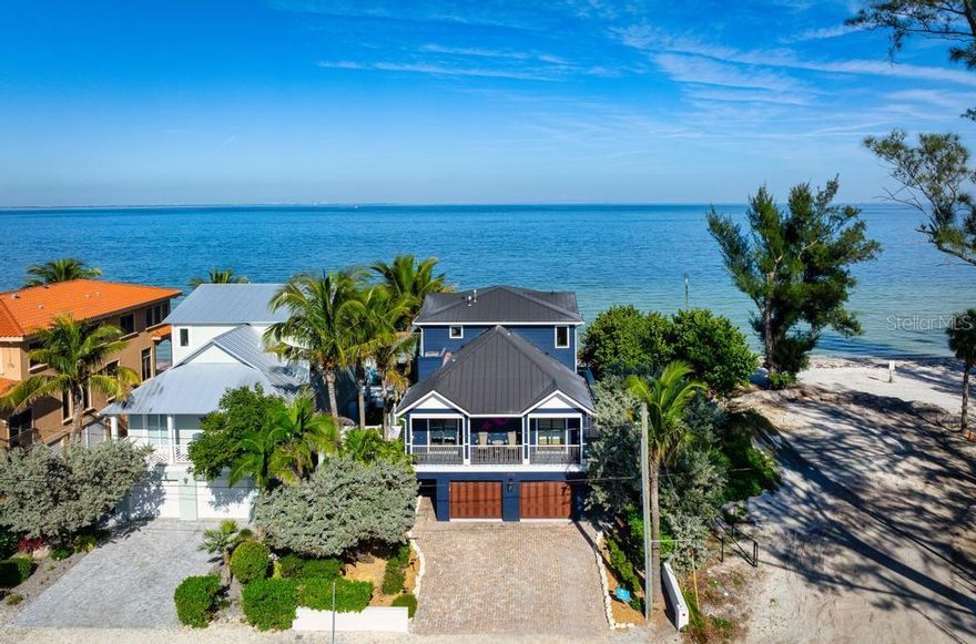 Direct Beachfront Luxury with Exceptional Rental Income on  Anna Maria Island. Discover the ultimate in coastal elegance with this direct beachfront home on the shores of Anna Maria Island. A rare beachfront home sold turnkey furnished that seamlessly blends refined luxury with a proven record of outstanding short-term rental performance. Recently enhanced with numerous upgrades including new sliding doors on the upper level—this home showcases high end finishes and expansive walls of glass that capture sweeping views of Tampa Bay and the iconic Sunshine Skyway Bridge. The spacious living and dining areas open through floor-to-ceiling sliders to a generous bayfront balcony, creating an effortless indoor–outdoor flow for entertaining or peaceful relaxation. The gourmet kitchen is a chef’s delight, featuring shaker cabinetry, a large island with seating, quartz countertops, and new premium stainless-steel appliances including a gas range. Each of the four bedrooms is a private retreat, complete with an en-suite bath and its own balcony framed by tropical scenery.  Additional recent upgrades include new ground-level outdoor furnishings, refreshed tropical landscaping with exterior lighting, and newly painted interior and exterior spaces. The covered poolside lounge and dining area on the ground level are the perfect setting for waterfront living—just steps from the sand. As evening falls, enjoy the mesmerizing glow of the Skyway Bridge from your own serene getaway.  Set on the pristine beachfront of Anna Maria Island, this home features timeless architecture, a spectacular coastal setting, and an unparalleled opportunity for both personal enjoyment and exceptional rental revenue.  This 4-bedroom, 4-bath residence produced nearly $500,000 for 2025,  $456,000 booked for 2024, and $464,000 in 2023. Future 2026 reservations in place Comprehensive rental history and future booking details for 2025 and 2026 are available upon request. A rare chance to own a true beachfront sanctuary.