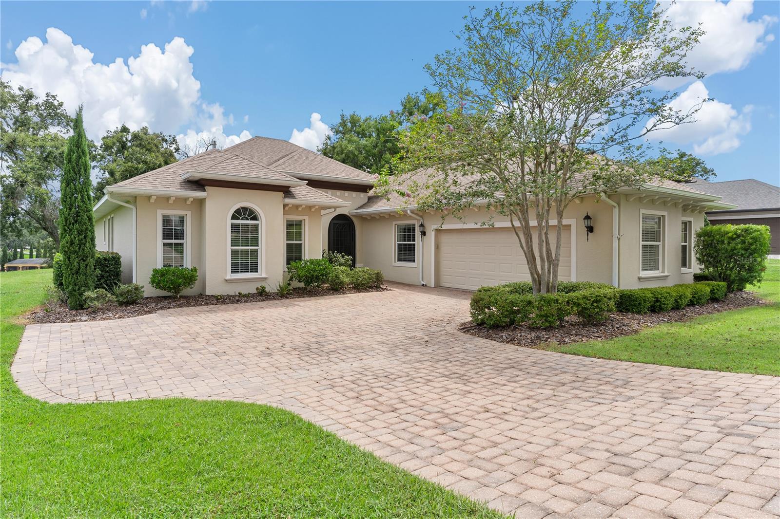 AMAZING HOME...UNIQUE IN DESIGN! Look no further and don't miss this golden opportunity to own this stunning four-bedroom, three-bath home featuring 3 en suites! Located on the 6th fairway with spectacular views in a secure, 24/7 guard gated, prestigious Golfing Community! The brick paver driveway greets you as you step through the front screen porch to enter your "move in ready"...like new home! This residence features a bright and airy open-concept layout with a 3-way split floor plan! Soaring ceilings and wall-to-wall sliding glass doors flood the space with natural light and frame breathtaking golf course views. The oversized foyer leads you to the heart of the home... the spacious kitchen! Fit for the chef, this gourmet kitchen blends functionality with style—complete with a large center island, granite countertops, stainless steel appliances to include a double oven range, two pantries, abundant cabinetry with pull out shelving/ drawers and a wine bar with a built-in wine rack and wine cooler. The elegant dining area showcases a sparkling crystal chandelier and direct access to the lanai, perfect for effortless indoor-outdoor entertaining. The spacious great room is enhanced by a cozy stone gas fireplace for "romantic evenings" at home! Enter through double doors to your luxurious primary suite offering a spa-like retreat with dual raised vanities, oversized soaking tub, walk-in shower, water closet for privacy, two generous walk-in closets, automatic window shades and serene views of the fairway. En suite #2 with walk in closet include its own bathroom features a pocket door to hall, servicing guests & bedroom 4 with huge walk-in closet! In addition, enjoy en suite 3 with its own private bath! Convenient inside laundry room with lots of cabinets & built in sink! The oversized screened lanai—equipped with an automatic screen—overlooks the lush golf course and offers a peaceful outdoor sanctuary. The backyard, enclosed by a new black iron fence with a 6-foot gate, is adorned with blooming Confederate jasmine for added privacy and beauty, perfect area for your kids to play or your pet to roam freely...Additional highlights include: A deep 2.5-car garage includes extra space (11 x 9.6) for golf cart or extra storage Custom wood cabinetry, real oak hardwood and porcelain tile flooring Upgraded LED recessed lighting and oversized ceiling fans Recent updates such as: Full interior repaint (walls, doors, moldings, baseboards). New crystal light fixtures in foyer and dining room Premium hardwood oak flooring. The residents enjoy privacy and tranquility just minutes from The Villages. In addition to the HOA cost there is a Monthly Minimum Social Membership Required of $180 per month offering access to a wide range of luxury amenities to include clubhouse with fitness center, Olympic size pool, tennis, racquet and pickle ball! Plus, access to boating/fishing on the Harris Chain of Lakes!! For additional fees...Golf membership and RV/Boat storage available. This home seamlessly blends luxury, comfort, and resort-style living in one of Central Florida’s most desirable golf communities. Call today for the start of your new beginning vacationing from home!
