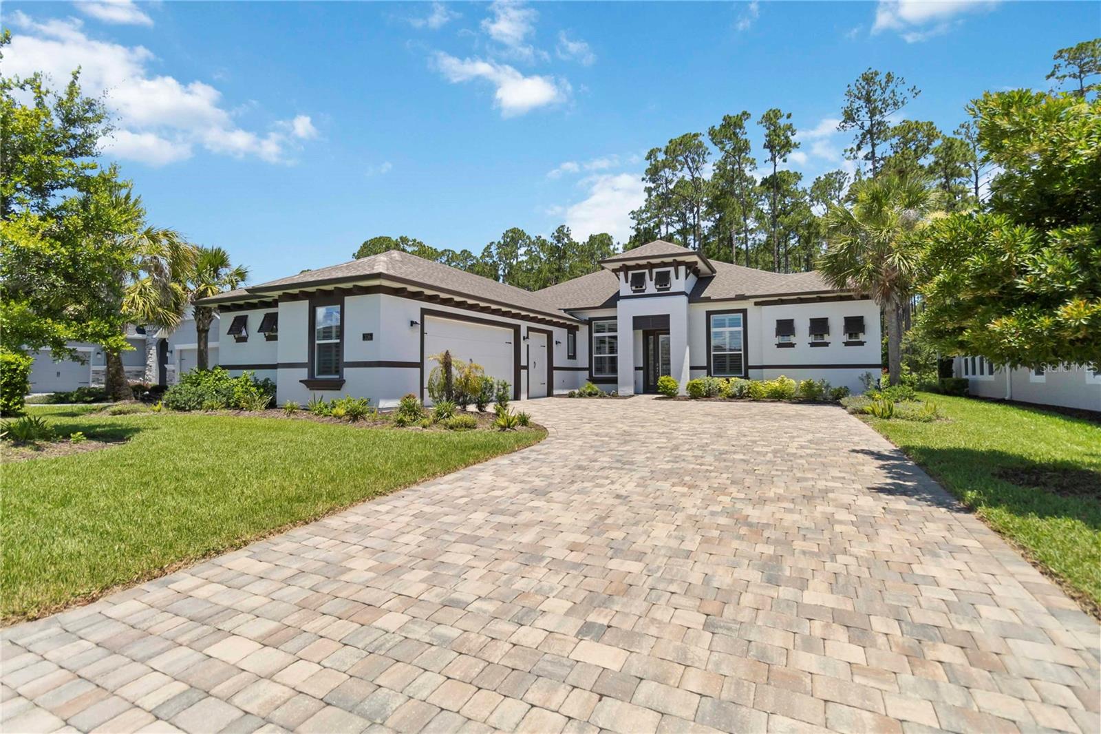 One or more photo(s) has been virtually staged. Live the resort lifestyle at 336 Stirling Bridge Drive, nestled in the desired, 24-hour manned-gated golf community of Plantation Bay in Ormond Beach. Step inside to an open, light-filled layout designed for effortless living and entertaining. Triple sliders blur the line between indoors and out, leading to a private poolside retreat ideal for year-round gatherings. A custom electric fireplace with reclaimed wood mantel anchors the living space, adding warmth to the modern design. Volume and tray ceilings lend elegance and spaciousness throughout. The chef’s kitchen is both beautiful and functional, featuring quartz counters, a tile backsplash, premium stainless appliances, 42” soft-close cabinetry with dovetail drawers, and a large island with breakfast bar. A cozy nook overlooks the lanai and pool—perfect for everyday living. This ICI Egret VI model boasts a desirable split-bedroom layout with four spacious bedrooms and custom built-ins. The serene primary suite offers bay windows, dual walk-in closets, tray ceiling, and a spa-like bath with dual vanities and a walk-in shower with seat. Need a home office or media space? The private den adds flexibility. Your outdoor oasis features a heated pool and spa under screened enclosure with ambient LED lighting. The summer kitchen—with propane grill and beverage fridge—makes entertaining easy. Enjoy added privacy with a backyard that backs to wooded conservation. Additional highlights include an oversized 3-car garage with epoxy floors, programmable soffit lighting, and pristine upkeep throughout. Optional membership at Plantation Bay offers 45 holes of championship golf, tennis and pickleball courts, two clubhouses, bocce, fitness centers, a resort-style pool, and endless social activities.