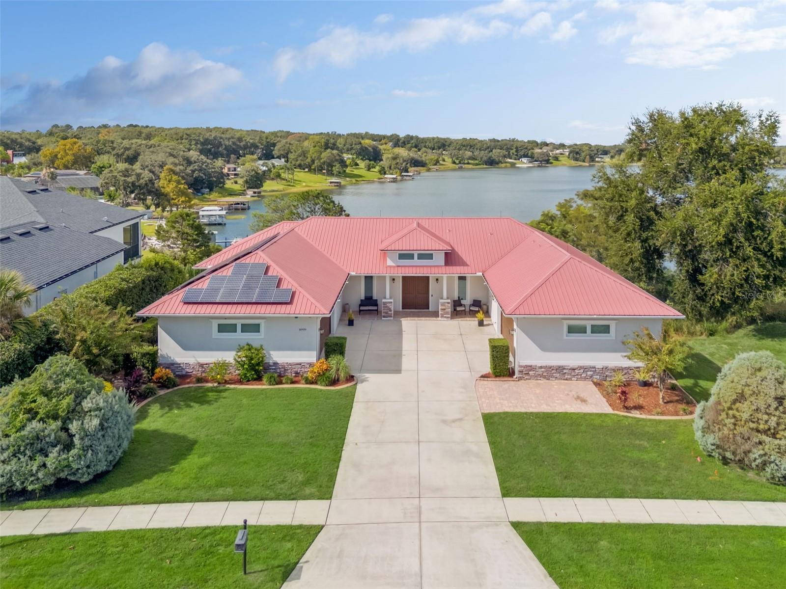 LAKEFRONT LUXURY IN MONTVERDE!
Discover your dream home on the shimmering shores of Lake Florence… a private, spring-fed 142 acre paradise and a short  distance of the renowned Montverde Academy. This stunning six-bedroom, four-and-a-half-bath pool home blends elegant design, energy efficiency, and the ultimate lakefront lifestyle.  
Step inside and be greeted by breathtaking water views from nearly every room. The chef-inspired kitchen features abundant and completely custom cabinetry, solid-surface countertops, a convenient wet bar/butler’s pantry, and plenty of space for family gatherings around a large dining table. The kitchen is complete with gas-stove, double ovens, separate ice maker/freezer, beverage refrigerator, and even a stand-alone induction cook top!.  Several appliances have recently been replaced.  Flow seamlessly into the inviting family room, where a cozy propane fireplace sets the stage for relaxed evenings and memorable entertaining.
Just beyond, the screened upper deck is the perfect spot for morning coffee or sunset cocktails overlooking the lake. The upper and lower patios, at 80 combined feet, provide an incredibly large area for hosting of friends while taking in jaw dropping lakeside sunsets! The downstairs screened patio features a built-in fireplace and a storm-proof television system.  The spacious primary suite offers serene lake views and a private retreat, while an adjacent bedroom (currently an office) and two additional bedrooms with two full baths provide ample space for family and guests.  As a bonus, there is a separate washer/dryer hookup in the master closet.  The house-wide central vacuum system makes cleaning a breeze!
Downstairs, the walkout lower level is an entertainer’s dream,  complete with a guest suite and kitchenette, a media room/theatre with stadium seating, two versatile bonus rooms for crafts or storage.  A large open area features a large, garage-style door to bring in fresh air from the deck- perfect for a home gym or recreational area.  Outside, enjoy your pool against the backdrop of Lake Florence or stroll down to your covered lakefront toy storage rack for a relaxing paddle.
Speaking of toys- one garage not enough?  This home features two full sized side-entry garages, one of which is cooled by a hybrid hot water heater!  Despite the very high garage ceilings, there is ample attic space, complete with spray foam insulation.  The landscaping is professional designed and easily maintained, including the ever-so-soft zoysia grass. The property uses both city and well-based water and a septic system efficiently manages waste.  Even down to the lightning rods on the metal roof, this property hits all the details!  
Outside, enjoy resort-style living: lounge by the pool, gather around the fire pit, play a match on your private sand volleyball court, launch watercraft from your private beach, or cast a line from your private and recently rebuilt dock. The covered boat dock with a touchless electric boat cover makes lake days effortless , just hop on your boat and explore the crystal-clear waters of Lake Florence!
Built with green living in mind, this home features ICF R50 concrete construction, R30 spray foam insulation throughout, solar panels, Energy Star double-pane windows, a 16 SEER AC unit, 50-gallon water heater, and a Generac whole house generator for peace of mind.
This is your opportunity to enjoy a terrace-style, walk out lakefront home- a rarity in Florida!