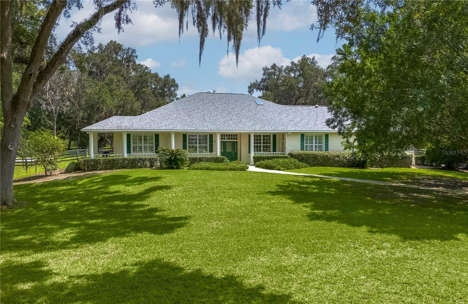 Discover an exceptional blend of luxury, privacy, and functionality on 4.20 acres in the sought-after, gated community of Alamar Village. This meticulously designed 5-bedroom, 4-bath estate spans 3,498 square feet and offers a flexible split-bedroom layout ideal for both everyday living and elegant entertaining. Set back from the road, mature landscaping and grand oak trees set the tone for this peaceful retreat. Inside, engineered wood flooring extends throughout the main living areas, with tile in the kitchen and baths. The heart of the home is the central living room which features a custom built-in entertainment center and French doors opening to the expansive pool area. The oversized kitchen is designed for those who enjoy cooking, featuring a center island, gas range, breakfast bar, wine rack, generous cabinet storage, and a walk-in pantry. A cozy breakfast nook with built-in bench seating overlooks the pool, while the formal dining room off the foyer and kitchen adds a touch of sophistication for hosting. A versatile library with extensive built-in shelving, a walk-in closet, and private full bath offers the perfect space for a home office, guest suite, or quiet reading room. The primary suite is a private haven with dual walk-in closets and an ensuite bathroom featuring dual vanities with under-lighting and a large walk-in shower. The lifestyle continues outdoors with a resort-style saltwater pool and spa surrounded by travertine decking and enclosed with a new screen cage. Enjoy shaded relaxation under a covered area with ceiling fan, an ideal for gatherings or quiet evenings that even includes an outdoor sink for added ease. Beyond the pool, the backyard is fenced with no-climb and board fencing and includes a separate patio area. Additional highlights include a utility hallway with extensive built-in storage, laundry area, and an extra refrigerator; a side-entry attached garage; and a multi-functional Morton building offering a 12’ x 28’ insulated room, 4-car garage, patio, and RV stall with electric hookup (per HOA, RVs may not be stored outside). Set in a tranquil, equestrian-friendly setting near Ocala’s Florida Horse Park and the Cross Florida Greenway’s expansive trail systems, this property offers space, serenity, and sophistication– perfect for those seeking a luxury lifestyle with room to live and breathe!