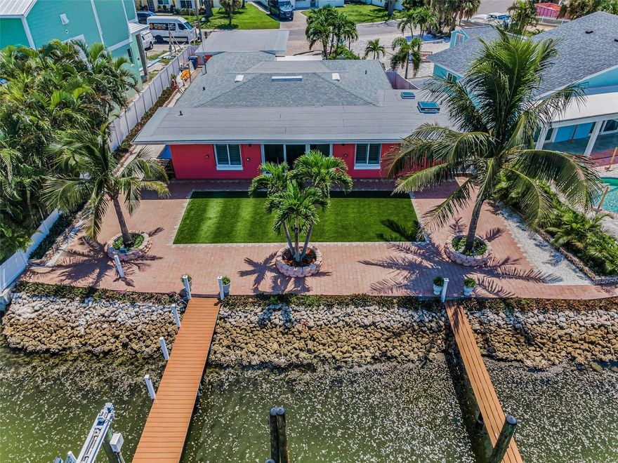 Turn-key 4BR/2BA Madeira Beach waterfront home with 71 feet of seawall, deep-water access, a 10,000-lb Davit Master boat lift, and additional berths for boats up to 38 feet. The entire waterfront side of the home features impact-rated sliders and PGT windows to capture stunning views. Watch dolphins play morning and night, and enjoy breathtaking sunrise and sunset views right from your backyard. The dock is fully equipped with electricity and water. Interior features include porcelain tile flooring, recessed lighting, plantation shutters, and a 19x13 bonus entry room with custom tile. The open-concept layout connects the living, kitchen, and dining areas to a peaceful flex nook outside the primary bedroom, perfect for reading, yoga, or a creative space. The kitchen offers quartz countertops, a gas stove, a wine cooler, and New stainless steel appliances. The primary suite includes dual vanities, a custom shower, a skylight, and a spacious walk-in closet. Other upgrades include a new 200-amp electric panel, mini-split units, a gas dryer, and blown-in attic insulation. The garage features a hurricane-rated door, LED lighting, and built-in storage. Additional highlights: whole-house water purification system, electric roll-down shutters, new gutters and drainage, and generator-ready propane hookup. Located just minutes from open Gulf waters. Walking distance to the beach and just down the block from the Elks Lodge, where you can sit poolside. This is authentic coastal living. Don’t let this one get away.