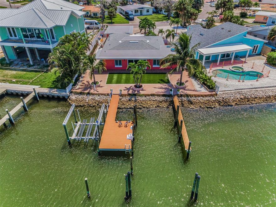 Turn-key 4BR/2BA Madeira Beach waterfront home with 71 feet of seawall, deep-water access, a 10,000-lb Davit Master boat lift, and additional berths for boats up to 38 feet. The entire waterfront side of the home features impact-rated sliders and PGT windows to capture stunning views. Watch dolphins play morning and night, and enjoy breathtaking sunrise and sunset views right from your backyard. The dock is fully equipped with electricity and water. Interior features include porcelain tile flooring, recessed lighting, plantation shutters, and a 19x13 bonus entry room with custom tile. The open-concept layout connects the living, kitchen, and dining areas to a peaceful flex nook outside the primary bedroom, perfect for reading, yoga, or a creative space. The kitchen offers quartz countertops, a gas stove, a wine cooler, and New stainless steel appliances. The primary suite includes dual vanities, a custom shower, a skylight, and a spacious walk-in closet. Other upgrades include a new 200-amp electric panel, mini-split units, a gas dryer, and blown-in attic insulation. The garage features a hurricane-rated door, LED lighting, and built-in storage. Additional highlights: whole-house water purification system, electric roll-down shutters, new gutters and drainage, and generator-ready propane hookup. Located just minutes from open Gulf waters. Walking distance to the beach and just down the block from the Elks Lodge, where you can sit poolside. This is authentic coastal living. Don’t let this one get away.