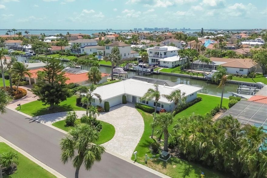 Welcome to your own piece of paradise in the prestigious Country Club Shores neighborhood on Longboat Key. This stunning 4-bedroom, 3-bath home has been thoughtfully renovated with a perfect blend of coastal elegance and modern sophistication, offering ideal indoor-outdoor living along one of the island’s serene canals. Inside, you’ll be welcomed by a bright, open-concept design featuring beautiful, engineered wood floors, custom beadboard ceilings, and a soothing palette of sea-glass blues and clean whites. The heart of the home is a gourmet kitchen outfitted with stainless steel appliances, designer pendant lighting, and stylish lattice-front cabinetry. A large island anchors the space, perfect for entertaining, while the adjacent living area boasts custom-built-ins, a sleek gas fireplace, and expansive views that flow effortlessly outdoors. Each bedroom is designed for comfort and privacy, with spa-inspired bathrooms that feature elegant tile work, modern fixtures, and soft lighting. The primary suite is a retreat of its own, with custom shelving, cozy window seats, and lush garden views through plantation shutters. Step outside to experience Florida living at its finest. The spacious screened lanai surrounds a sparkling heated saltwater pool and paved deck, creating a private oasis perfect for lounging, swimming, or dining alfresco in total comfort. Just beyond, a large, newer dock awaits, offering deep-water canal access—an ideal setup for avid boaters and water lovers. The deck overlooking the canal is a peaceful setting for morning coffee or an evening cocktail This home also offers exclusive deeded beach access, just a short walk or bike ride away, where you can soak in the soft white sands and turquoise waters of the Gulf. When it’s time to explore, the renowned boutiques and fine dining of St. Armands Circle are just down the street, offering vibrant nightlife, unique shopping, and gourmet experiences in a picturesque coastal setting. A short drive over the scenic Ringling Bridge takes you to downtown Sarasota, a cultural haven known for its art galleries, theaters, opera house, and waterfront dining. Whether you're strolling through the Saturday farmers market, taking in a performance at the Sarasota Opera, or enjoying waterfront cocktails at Marina Jack, the city provides an enriching blend of sophistication and coastal charm. With its ideal location, timeless design, and luxurious updates, this home offers the very best of Longboat Key living—a rare opportunity to enjoy both boating and beachside leisure in one of Florida’s most coveted communities.