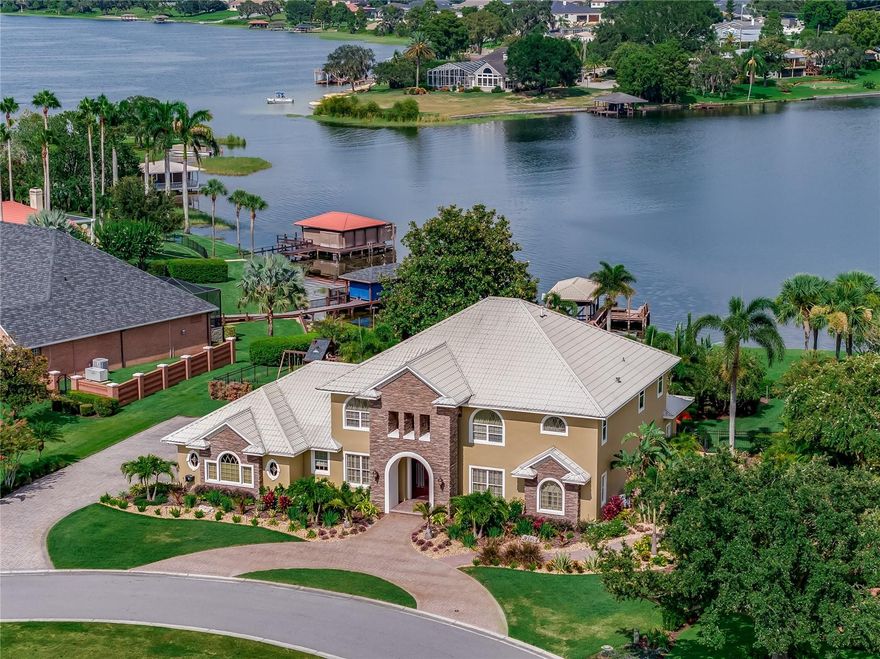 Stunning luxury lakefront residence located in the gated and guarded community of Renaissance in Winter Haven Florida. Introducing 246 McLean Point, a resort style retreat nestled along the pristine shores of Little Lake Winterset, part of the majestic Winter Haven Chain of Lakes. This remarkable pool home is the epitome of luxury living, boasting an impressive 5,555 sqft of living space, 5 bedrooms, 4 full baths, and an array of exquisite amenities. Grand double entry doors lead to an impressive two-story foyer adorned with gorgeous travertine flooring, intricate woodwork and striking finishes that flow throughout showcasing the craftsmanship of skilled artisans. The kitchen is a culinary enthusiast's dream, equipped with top-of-the-line appliances, including a stand-alone freezer and fridge, Viking gas range, convection wall oven, granite counters, custom cabinets, an island with an ice maker and a sink, a Miele coffee maker, and a hidden walk-in pantry. The open concept design seamlessly connects the kitchen to the adjacent dining area, family room, breakfast nook, and billiards room, making it ideal for comfortable living and entertaining guests. The formal dining room offers an exquisite tray ceiling with faux painting and an elegant chandelier for formal gatherings. The family room features custom built-in cabinetry, a stacked stone gas fireplace and panoramic views of the lakefront setting. Entertain with flair in the billiards room, complete with a well-stocked wet bar while additional wine storage can be found in the wine room under the staircase. The ground floor primary bedroom is a private sanctuary boasting breathtaking sunrise views over the lake, and an en-suite bath with double vanity, an elegant garden tub with a chandelier, a walk-in shower, and two fully customized walk-in closets. Additional ground level rooms include a pool/guest bath, an executive office and a laundry room. Venture to the second level where you'll discover another master suite offering elevated lake views and a luxurious bath with dual vanities, a copper tub, and a steam shower. The loft area is perfect for hosting guests, while the illuminated beauty bar room caters to glamorous makeup sessions or can serve as an additional bedroom or office. Two more guest bedrooms and a bath can also be found on this level, along with a home theater featuring a 120-inch screen, surround sound system, and plush theater seating for your favorite movie nights. The flow of this home is a canvas that seamlessly merges indoor and outdoor elements. The resort-style backyard is an oasis like no other, featuring travertine decking, covered lanai, outdoor kitchen with a grill and an infinity edge pool and spa all surrounded by memorizing gas fire bowls and a poolside fireplace. The composite material dock features remote-controlled cover for boat protection and the ideal launching point to enjoy all the Winter Haven Chain has to offer from waterfront dining, boating, skiing and fishing on over 20 canal-connected lakes. Whether admiring the crystal-clear water at the dock or entertaining loved ones inside the home, this property is the epitome of luxury and relaxation! Additional features include: a 45000 KW Generac generator, lake-fed irrigation system, mosquito sprayers, metal seawall, an air-conditioned 3 car garage, new grass, updated sprinkler system, new landscaping, Sonos surround sound and more. Come discover this once in a lifetime offering. Home comes furnished.