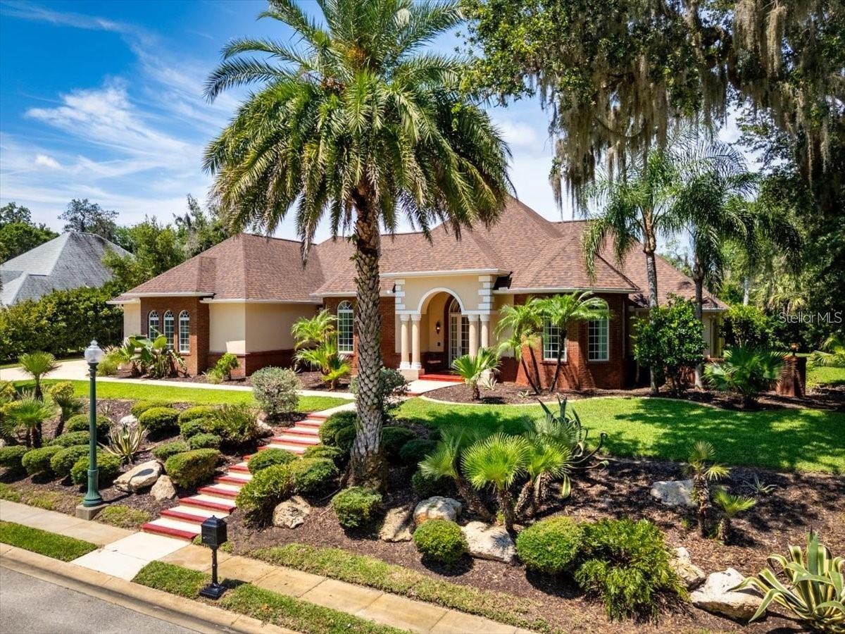 Tucked beneath towering oaks on a quiet cul-de-sac in prestigious gated Fairchild Oaks, this rare estate offers over 5,800 square feet including including a massive 1,000 square foot 4-car garage, all situated on one of only two double lots spanning over half an acre. The 3,832 square feet of luxurious living space flows from a chef's kitchen—featuring premium KitchenAid appliances including convection oven, gas range, wine cooler, and wet bar with roll-out drawers—into elegant entertaining areas with soaring tray ceilings, crown molding, surround sound, and a cozy gas fireplace. The master suite sanctuary boasts a spa-like light therapy jacuzzi tub, dual walk-in closets, dual-head shower with body jets, and separate bidet, while the backyard feels like a private nature preserve with mature landscaping and visiting wildlife. Built with quality throughout including concrete block construction, 2020 roof, 2024 main 5-ton AC system with 4-zone efficiency, dual water heaters including a new 2025 unit, hurricane-rated Pella windows with integrated blinds, smart 5-zone well-fed irrigation, gas patio hookup, pool wiring, and a concrete block safe room laundry with triple locked steel door. At $699,900, this exceptional home delivers incredible value at just $182.65 per square foot, offering coastal convenience with complete privacy just minutes from Flagler Beach.