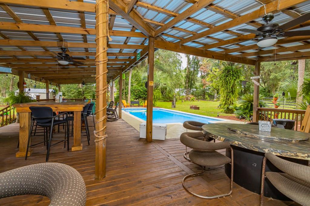 Florida living at its finest with this backyard oasis on 2 ½ acres, serenity and peacefullness rural living for your animals all within 10 minutes of the city of Ocala This 4 bedroom, 2.5 bath pool home. Is truly a hidden gem. The home has been recently updated. When entering the home, you notice the attention to detail with crown molding, 5 1/2 in. baseboard, 6 panel solid core doors with fluted trim, newer light fixtures, with plantation shutters on the newer windows. The kitchen is equipped with stainless steel appliances. A wine cooler, granite countertops with a breakfast bar and dining area that looks out to the stunning landscape in the front of the home. The owner's suite is very spacious with his and her closets, frosted glass doors, double frosted barndoors lead to the spa like retreat with large shower, double vanity, and your very own makeup station. The home has a flex space at the rear of the home with picture windows looking out to the 1400 square foot cover deck oasis. The deck has a half bath, wet bar, 2 overhead TV's, a high-top bar with electric plug ins, tons of seating areas all covered by metal roof. The soothing sound of those rainy nights! Take a swim in the 16x32 foot pool. The picturesque property backs up to a small pecan farm. 2 utility buildings are on the property. The grounds also include a 20x20 additional building with roll up garage door, that has a side door and electric with tons of storage above. An additional 14x20 building is included that makes a total of 4 buildings on the property. Pride of ownership shows inside and out of this unique property tranquility is awaiting it is a one of a kind once you are here it is hard to leave. Enjoy everything that Ocala has to enjoy. within minutes to biking trails, shopping, restaurants,. Enjoy country living while being minutes from everything.