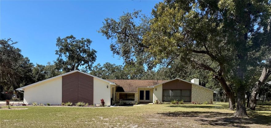 This spacious 4-bedroom, 2-bathroom home sits on a full acre zoned agriculture and features an open-concept, split floorplan with a large living room offering recessed lighting, new vinyl flooring, and a wood-burning fireplace. The kitchen provides abundant storage, a center island, and an air stone backsplash, flowing seamlessly into the main living area. The primary bedroom includes an en suite bathroom, while the three additional bedrooms each have walk-in closets, and the second bathroom uniquely includes two showers. Additional highlights include a laundry room with extra storage and a separate building perfect for storage with a one-car garage. Located just 2 miles from shopping, restaurants, and the hospital, and only 3 miles from the Suncoast Parkway, this property offers comfort, convenience, and the flexibility of agricultural zoning on a beautiful acre of land.