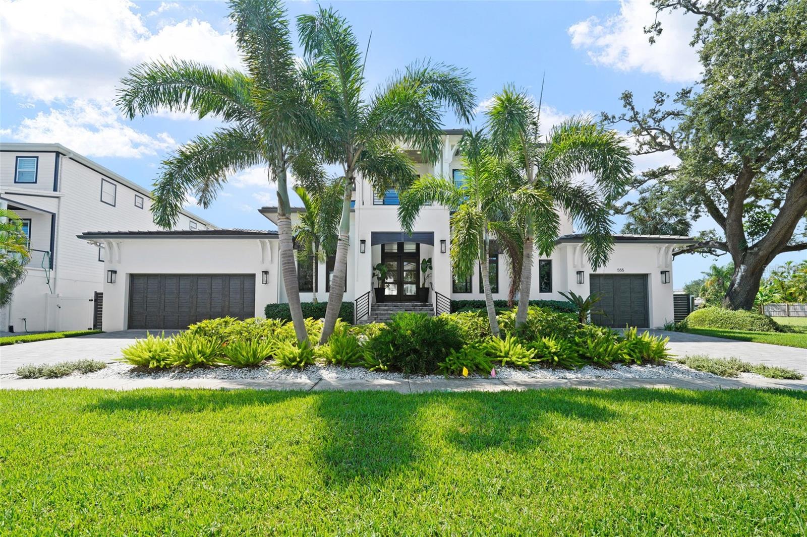 Davis Islands Modern Coastal on 100’+ of Waterfront with first-floor master bedroom. This custom-built residence blends timeless design with the highest standards of craftsmanship and is located on a quiet street on Davis Islands.
The entry showcases a custom contemporary mahogany six-panel front door with impact glass and transom, opening to light-filled interiors defined by white oak engineered hardwood floors. A glass-fronted refrigerated wine cellar—with split-system cooling, floor-to-ceiling wood tile, stainless steel wine racks, a mahogany solid wood door, marble floors, custom cabinetry, and an electronic lock—serves as both functional storage and a striking design feature. The chef’s kitchen pairs marble counters and backsplash with premium appliances, complemented by a butler’s pantry and walk-in pantry. Living areas flow seamlessly to the outdoors through a 4-panel impact pocket slider, while PGT high-impact bronze windows with transoms on the front and rear elevations frame every view. Every element of the home reflects thoughtful engineering and luxury detail—from its piling foundation and concrete flat tile roof to the light sand finish stucco and custom Bahamian shutters with crafted metal railings and fencing that frame the façade. The primary suite offers two walk-in closets and a spa bath finished with imported marble flooring, counters, and shower, plus a freestanding soaking tub. Additional bedrooms include en-suite baths with marble finishes, continuing the home’s refined material palette.. At the water’s edge, a new seawall supports a composite dock with a covered 13,500lb boat lift—finished with a metal roof, lighting, water, and electric service. An additional electric 1,500lb lift lowers directly into the water, easing access for boating or water toys. The backyard is a showcase for Florida living: a contemporary rectangular saltwater pool with water-edge spa, glass waterline tile, umbrella stand, lounge area, and automated Hayward LED lighting. Surrounding the pool and lanai, silver travertine pavers set the stage for gatherings. The lanai’s cypress coffered ceiling frames a linear gas fireplace with a tabby shell stucco surround and a custom barnwood mantel, while a custom outdoor kitchen—featuring a Blaze grill and smoker with a double hood, stainless steel backsplash, beverage center, concrete counters, sink, and an Ipe wood surround—makes entertaining effortless. A plumbed outdoor shower with hot and cold water completes the resort feel. Six gas lanterns accent the entry and garages, bringing coastal character to evening hours. The oversized three-car garage offers versatility with a deep two-car bay (workbench and storage included) and an extended one-car garage sized for a golf cart. A whole-house generator ensures comfort and security year-round. Come enjoy the DI lifestyle with its walking and bike path, and just a short distance away from Davis Islands Village with many restaurants, shops, and bars. Bring your golf cart and enjoy the Island lifestyle with baseball fields, public tennis courts, a public historic pool, two dog parks (one wet and one dry), a beach, a public marina, and an airport. Located only minutes from Downtown Tampa, Water Street, Sparkman Wharf, and the Tampa Riverwalk, this neighborhood is the most desired in South Tampa!