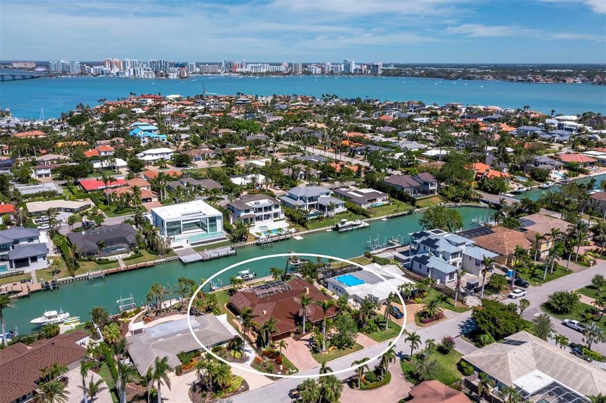 This stunning waterfront home on Bird Key, one of Sarasota’s most desirable locations, offers a perfect blend of style, comfort, and direct access to the water. The 3-bedroom, 3-bathroom, 3,425+/- sq. ft. residence is complemented by a circular paver driveway and mature landscaping, creating a welcoming first impression. Inside, the home features tile floors, neutral tones, and black crown molding, creating a clean, elegant atmosphere. The spacious living area is ideal for both relaxing and entertaining, with a custom-built entertainment center, wine refrigerator, and a fireplace. Large windows open to the screened outdoor living space, bringing in natural light and waterfront views. The kitchen is well-appointed with wood floors, custom cabinetry, a center island with cooktop, a tile backsplash, stone countertops, and stainless-steel appliances. The primary suite offers vaulted ceilings, a wall of glass doors with plantation shutters opening to the pool, and an adjoining office. The suite also includes a large custom closet and a spa-like bath with a walk-in shower, spa tub, and dual vanities. Guest rooms provide privacy and comfort, with thoughtful design throughout. One of the guest bedrooms includes an additional sitting room/den, offering a quiet retreat or flexible space. The screened lanai is perfect for outdoor living, with a covered sitting area, summer kitchen, and a pool with a custom large hot tub and rock waterfall. Beyond the lanai, an open paver patio overlooks the canal and leads to a private dock with a boat lift and jet ski lift, which can also accommodate kayaks or other watercraft. This home was unaffected by the recent hurricanes, with no water intrusion, offering peace of mind and resilience in a prime waterfront location. As a resident of Bird Key, you also have optional access to the exclusive Bird Key Yacht Club, which offers a variety of amenities including a marina, fitness center, dining, and social events. Enjoy boating from your backyard, walking tree-lined streets, and being just minutes from St. Armands Circle and downtown Sarasota.