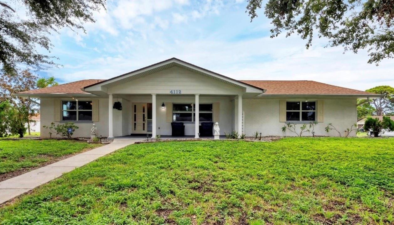 One or more photo(s) has been virtually staged. This is a wonderful opportunity to become the new owner of this Pine Lakes 3 bedroom 2 bath home, 2.5 car garage centrally located in West Bradenton. A charming covered front porch invites you into a home that has been lovingly maintained and attractively updated. Inside you'll find beautiful Brazilian Cherry wood flooring in the main living area. A remodeled large kitchen will have you smiling with its abundant storage options and showcases solid wood cabinetry, lit-up glass display doors, granite countertops, a farmer's sink, smudge-free stainless steel appliances along with a ceiling mounted range hood and a desk station. The split plan layout is perfect with a formal dining and living room in addition to a breakfast nook and a HUGE 28 x 12 family room. Both bathrooms are tastefully updated and feature custom wood cabinetry in two of the bedroom closets to help keep your items organized. The big ticket items are covered for you with a 2022 roof, a 2016 4 Ton A/C, 15 impact windows installed in 2008 and a 2016 water heater. The sprinkler system that includes a well will maintain your lawn keeping it lush and green while saving you $ on your watering bill. Additional features include attic storage, wheelchair accessible features and a large oversized two car garage that offers potential to be air conditioned for your workshop or gym. Relax in the privacy of your screened porch and backyard which will be the perfect romping grounds for little ones and pets. This immaculate home is located in an X non-flood zone and has no HOA or CDD fees.