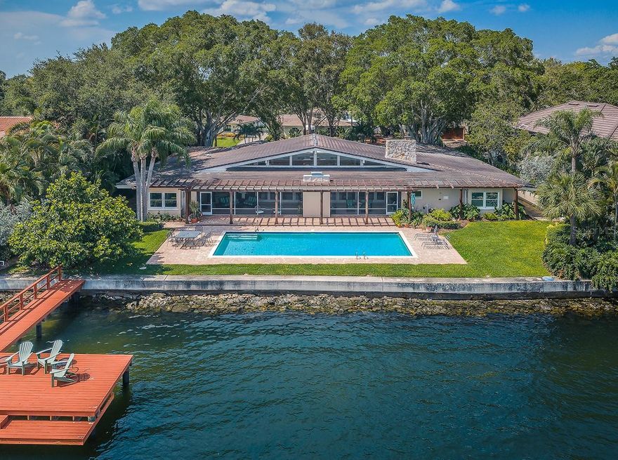 LOCATED ON A WIDE, OVERSIZED LOT IN THE HEART OF SNELL ISLE, WITH BEAUTIFUL OPEN WATER VIEWS OF TAMPA BAY, THIS UNIQUE, MID-CENTURY MODERN ESTATE RESIDENCE WAS BUILT WITH AN EXTRAORDINARY LEVEL OF PRECISION AND FORETHOUGHT! Attractively landscaped with a gated brick-paver circular driveway and extensively focused on the waterfront living experience, you’ll love the engaging and inviting feel of this home’s 6270 sqft of sweeping living area. Rich architectural design assures plenty of interior natural light all day long. An attractive covered entry opens to a generous 350sqft foyer and dazzling waterviews day and night. Overlooking the waterfront, step into the majestic 660sqft great room with towering 17ft-high vaulted ceilings and superb woodworking throughout. Your updated kitchen enjoys coastal-white cabinetry, lovely granite surfaces with complementary glass tile backsplash, a multi-level breakfast bar, Subzero Refrigeration, a splendid walk-in pantry and excellent water views. Casual and formal dining both overlook the pool deck and waterway, as does the spacious family room with fireplace. Take in the impressive 650sqft multi-purpose game room/media room with ample storage and adjoining full bath. The pleasing owner’s wing features a graceful owner’s bedroom with sitting area overlooking the waterfront. The substantial owner’s bath offers a luxury built-in dresser, dual vanities, a dedicated cosmetics center, oversized walk-in shower and walk-in closet. Additionally, the owner’s wing boasts a grand executive office with built-ins, a private ½ bath and a fitness/reading room. The guest bedroom wing boasts 3 large bedrooms (one overlooking the waterfront), built-in dressers, and extensive closet and storage space. Your main living areas opens to a 58ft-wide 738sqft screen-enclosed indoor-outdoor waterfront lanai with elegant wetbar – a tremendous space for entertaining. Out back you’ll discover a wonderful 60ft-wide pergola that is ideal for partially-shaded pool-side lounging. A superb brick paver deck encapsulates the huge deep-water swimming pool. Your wide lot and deep, protected boating water accommodates a 70+ ft yacht. Superior custom wood finishes, plantation shutters, privacy walls on both sides of the home, updated seawall/dock and many extras. Well-located near exceptional schools, fine dining and downtown St. Petersburg. Don’t miss this outstanding Brightwaters opportunity! Dimensions are estimates, buyer to confirm.