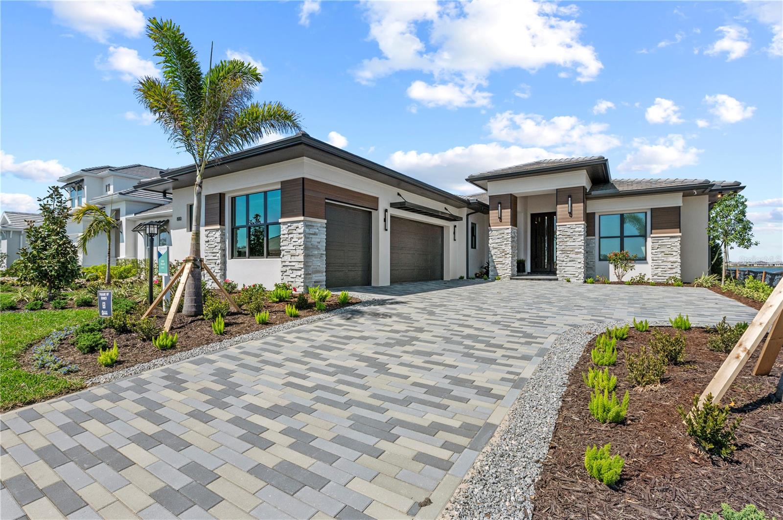 * A Unique Opportunity to own one of Lee Wetherington Homes highly sought after model homes in Shellstone at Waterside. This is a Purchase & Lease-back opportunity. The model is fully furnished and the purchase price is net of the first 12 months leaseback.
* A Stunning Custom Residence
Nestled in Shellstone at Waterside, the Sand Dollar is a breathtaking 3,289-square-foot custom home, featuring 3 bedrooms, 4 bathrooms, and a spacious bonus room, all designed with an unmatched level of sophistication and elegance.
* Grand Entrance & Thoughtful Design
As you step through the towering custom iron entry doors, you’re welcomed by exquisite ceiling details, soft indirect lighting, and a rich blend of warm wood tones, accented by touches of teal and soft gold. Every element of this home is designed with both beauty and function in mind.
* A Chef’s Dream Kitchen
At the heart of the home is the stunning angled kitchen, a masterpiece of form and function. The expansive island offers ample space for both cooking and entertaining, while the sleek contemporary cabinetry adds a touch of modern elegance.
* The Hidden Butler’s Pantry
Discreetly tucked away behind the main kitchen, the hidden Butler’s pantry provides additional prep space and storage, keeping everything effortlessly organized.
* Seamless Indoor-Outdoor Living
One of the home’s many showstoppers is the 12-foot glass door wall, which pockets away, dissolving the boundary between indoors and out, and opening to a spectacular outdoor living & dining space.
* Resort-Style Outdoor Oasis
Step outside and experience the ultimate Florida lifestyle. A fully equipped summer kitchen, a spacious dining area, and a comfortable lounging area create the perfect setting for entertaining. And just beyond, the breathtaking infinity-edge pool and spa, perfectly positioned to capture unparalleled views of the 200-acre Lake Merganser.
* Private Guest Retreats
The two spacious guest ensuites provide a private and luxurious retreat, ensuring that visitors feel completely at home.
* A Primary Suite Like No Other
Hidden behind a wall of custom wood panels, the primary suite is the ultimate sanctuary. Soft lighting, tranquil colors, and breathtaking lake views create a serene escape. French doors lead directly to the pool and spa, offering a seamless connection to the outdoors.
* A Spa-Inspired Primary Bath
The spa-like bathroom is a haven of relaxation, featuring luxurious finishes, an elegant soaking tub, and a spacious walk-in shower.
* A Thoughtfully Designed Laundry & Mudroom
Even daily tasks feel indulgent in the thoughtfully designed laundry room. The drop zone serves as more than just a mudroom—it’s a dream for pet lovers, featuring a built-in dog feeding station, a cozy dog bed nook, and a hidden dog gate. Every detail has been carefully considered.
* The Ultimate Bonus Room
When it’s time to unwind, the bonus room is the perfect retreat. A sleek wet bar, plush furnishings, and a cozy ambiance make it the ideal space to kick back, relax and enjoy a great movie.
* A Statement of Luxury & Elegance
* The Sand Dollar isn’t just a home—it’s a masterpiece of luxury, comfort, and modern elegance.