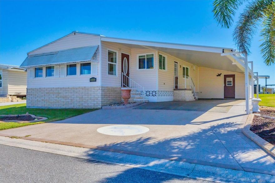 You'll love living in Tidevue Estates, a active 55+ land-owned community! This beautifully maintained home features an extra-large carport with ample space to create your dream outdoor living area—perfect for entertaining. Inside, you'll find a spacious kitchen with rich maple cabinets, granite countertops, two bright windows, and a convenient appliance garage to keep your counters clutter-free. Enjoy casual meals at the breakfast counter or host dinners in the formal dining room, complete with a built-in china cabinet and granite serving area.
The open-concept living room flows seamlessly into a light-filled Florida room, with a wall of windows and a leaded glass front door. Vaulted ceilings and laminate flooring throughout add to the home's airy and modern feel. The expansive primary bedroom (18x12) has transom windows to let the light in, a walk-in closet, and a luxurious ensuite bath featuring dual granite sinks, a river rock tile walk-in shower, and a dedicated make-up vanity. Additional highlights include a shed with double doors for golf cart parking, a workshop/craft area, and a washer/dryer. The carport roof was replaced in 2025. Enjoy the active lifestyle and amenities of Tidevue Estates in this move-in-ready gem! Low HOA of only $600 annually. Pets are not permitted. Plenty of activities to keep you busy in this community. Updated fitness room. Meet friends and make new ones for a game of indoor pickle ball, bocce ball, shuffleboard or take a water aerobics class. Join the Golf League. Take a bike or golf cart ride to Veterans' Park to watch the wildlife and sunset. Ellenton Premium Outlet Mall, restaurants, and medical facility's just minutes away. Easy access to I-75. Just a short drive to our beautiful Gulf Beaches. Tidevue Estates offers a vibrant lifestyle with no lot rent and a strong sense of community. This is Florida living at its finest!