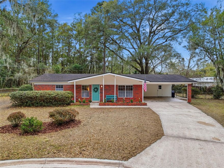 Under contract-accepting backup offers. Perfectly positioned at the back of a quiet cul de sac in a location that makes getting anywhere in Gainesville simple and convenient, this concrete block home combines charm, updates, and peace of mind. Just minutes to the University of Florida, Santa Fe College, hospitals, shopping, dining, and all that Gainesville has to offer, the setting offers both accessibility and privacy. Darling curb appeal with classic brick detail and a welcoming front porch set the tone as you arrive. Step inside to an open floor plan featuring new luxury vinyl plank flooring that flows through the main living areas. The spacious kitchen overlooks the dining area and large living room, creating an easy, connected layout ideal for everyday living and entertaining. The kitchen is appointed with newer appliances, a tile backsplash, painted brick detail, and a door leading directly to the carport for added convenience. Down the hall you will find a laundry closet with additional storage, along with three comfortable bedrooms and two bathrooms. The bathrooms have been updated with modern vanities, offering a fresh and clean feel. One of the standout features of this home is the huge screened patio that significantly expands the usable living space, perfect for relaxing or hosting gatherings year round. The large fenced backyard offers privacy with no rear neighbors, creating a peaceful outdoor retreat. Major system upgrades have already been completed, including a replaced septic and drain field, electrical upgrade, full replumb (2019), water heater (2019), and HVAC (2021). The seller is also willing to install a new roof with an acceptable offer, providing even more value and confidence for the next owner. This move in ready home offers comfort, updates, and an unbeatable location all in one inviting package.