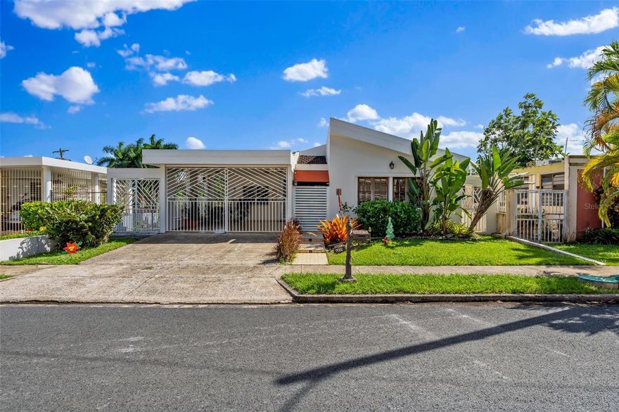 Gated community with 24-hour security guards, offering privacy and peace of mind in a central location with easy access to main roads, banks, and shopping centers. The residence features direct street access and offers a very comfortable and spacious layout with excellent natural ventilation. The property includes a covered carport with an electric gate. On the main level, the home offers three generously sized bedrooms and two full bathrooms.

Upon entering through the main entrance, a welcoming foyer leads into a spacious living area with high ceilings, providing abundant natural light and an open feel. This area flows seamlessly, separated by a half wall, into the kitchen and dining area, creating an ideal space for family living and entertaining.

From the social area, you can access a spacious terrace overlooking the backyard located on a lower level, perfect for outdoor activities. The backyard includes independent side access, making maintenance and use of the outdoor space convenient and functional.

The property has no rear neighbors, allowing enjoyment of an adjacent green area that provides added privacy and a tranquil setting.