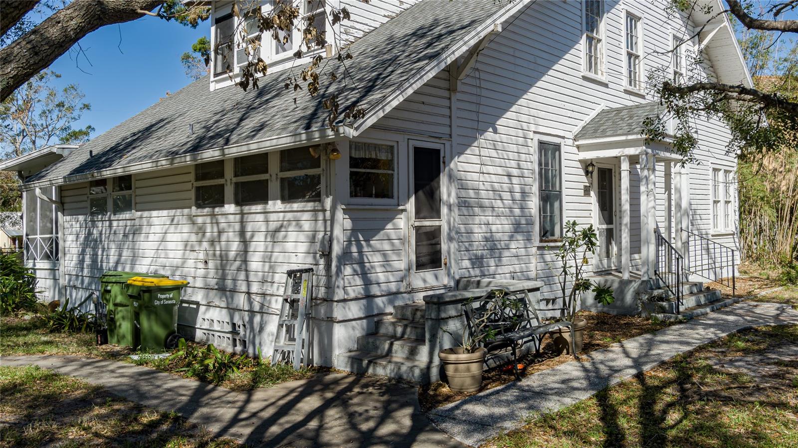 If only these walls could talk! Presenting 908 Pomelo Avenue—a century-old bungalow-style property that offers a rare opportunity for today's buyer to own a true piece of Sarasota’s historic charm. This historically registered homestead is situated on two and a half lots in the heart of Sarasota, in close proximity to public access points on Hudson Bayou and a short drive to downtown, beautiful Gulf beaches, and Selby Gardens. The main house features approximately 2,400 square feet of living space, with communal kitchen and dining areas on the lower level, and four bedrooms and two bathrooms on the second level. At the rear of the main house, you'll find a spacious screened sun porch overlooking a large swimming pool. Additionally, there is a detached two-car garage with a three-room apartment at the back, which could serve as extra space for the homeowner or as an income-producing investment.
This home is not subject to deed restrictions. While it may need some cosmetic updates, the property has “good bones,” and many significant renovations have already been completed. The plumbing and electrical systems were updated in 2003, and the roof was replaced in 2023. This property is ideal for a serious buyer who is ready to undertake a project that can transform it into an absolute showpiece. Disclosure: This property requires renovation and is recorded in the City of Sarasota Register of Historic Places, which means it is bound by specific regulations for alterations. The property is priced accordingly to reflect these constraints.