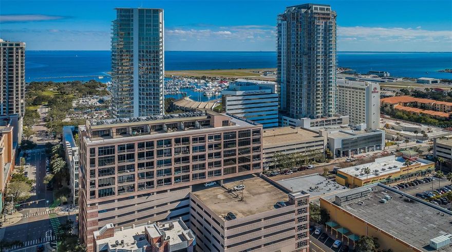 EXPERIENCE STUNNING WATER AND BUSTLING DOWNTOWN VIEWS IN THIS RARE SE CORNER, URBAN CHIC UNIT IN THE HEART OF DOWNTOWN ST PETE | This unique corner unit, located in the McNulty Lofts, offers a prime location near to all that downtown St. Pete has to offer.

Step inside and discover a completely updated living space with bamboo floors, automated blinds, and Bartels sliding barn doors. The custom-designed built-ins include an oversized display cabinet and an art gallery rail system perfect for showcasing your artwork. The kitchen is a chef's dream with HanStone quartz counters, custom 34-inch African Sapele cabinets, and a host of stylish upgrades including tile backsplash, heavy-duty drawers, sliders, and lazy Susan storage. Stainless steel appliances include GE Profile induction cooktop and dual ovens, a Dacor push-button drawer-style microwave, smart dishwasher, wine cooler, and upgraded "Bespoke" Samsung refrigerator with convenient in-door automatic filtered water pitcher.

Notable upgrades that enhance your living experience include a tankless hot water heater, a water softener system for the entire unit, and 200-amp electrical service (compared to 125-amp in other units). Stay comfortable year-round with a 2-ton air conditioner (an upgrade from the original 1.5-ton unit), and enjoy energy-efficient hurricane windows and sliders treated with Panorama Slate-20 window film and Hunter Douglas Silhouette shades.

With two secure parking spaces (one under cover) conveniently located steps from the elevator, you'll have easy access to your new home. The master bath features a large walk-in shower and a heated towel warmer with a digital timer.

This condo is move-in ready, allowing you to bask in comfort and style while enjoying views of cruise ships departing from Tampa Bay and the vibrant downtown scene. Don't miss out on this opportunity to embrace true upscale urban loft living at its finest.