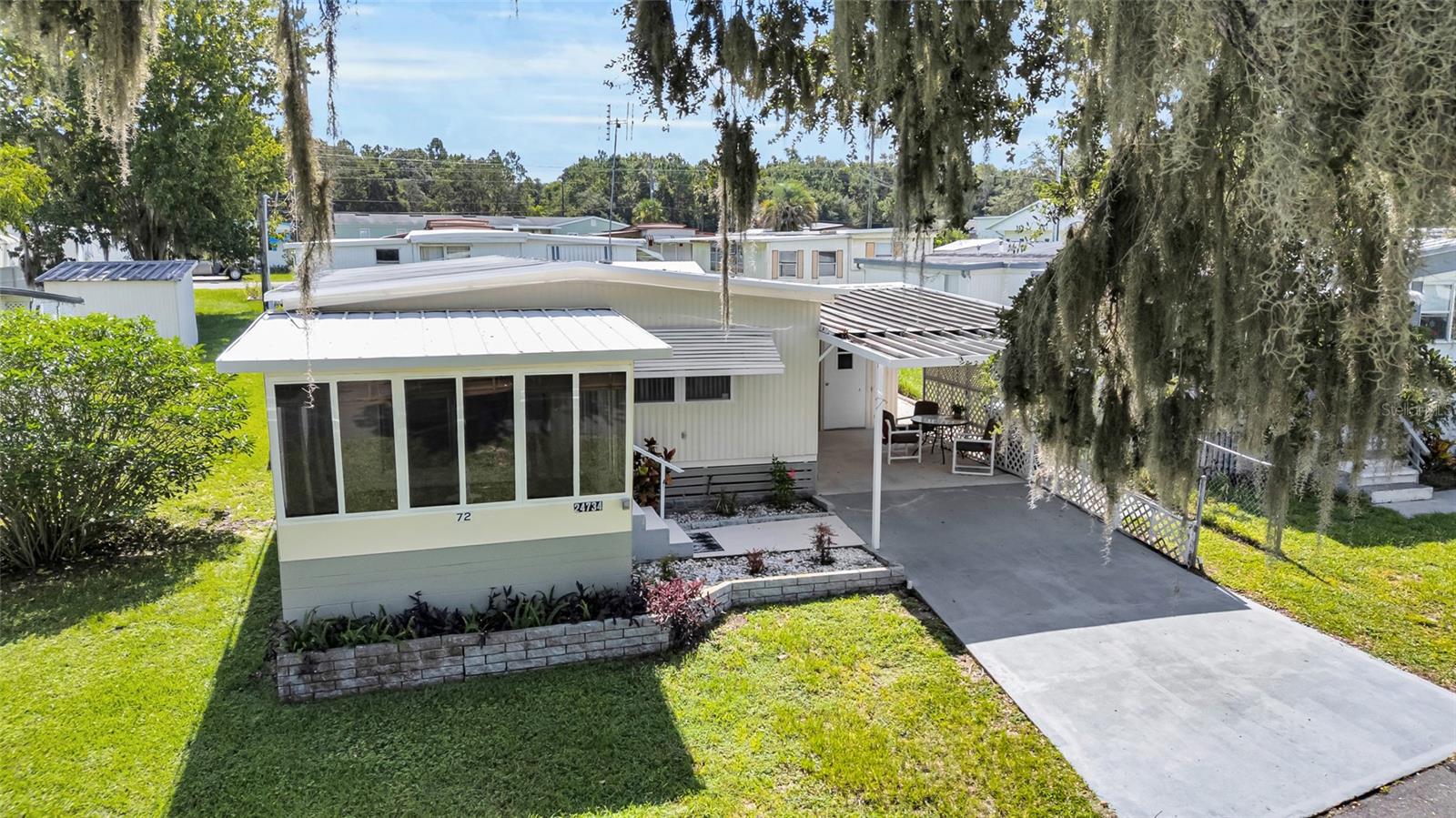 NO BOND, NO 55+, NO HOA, NO LOT RENT! This well maintained home has updated bathrooms and vinyl flooring throughout. The front porch is enclosed with large sliding windows so you can enjoy the view of the pond across the road. This home offers a kitchen with plenty of cabinets, a nice dining room and a very large living room. The large primary bedroom has a half bath ensuite that connects to the guest bath. There is a large laundry room with window unit and closet for additional storage as well as a storage room in the car port. In the partially fenced back yard, there is another storage shed. The home is freshly painted inside and out.