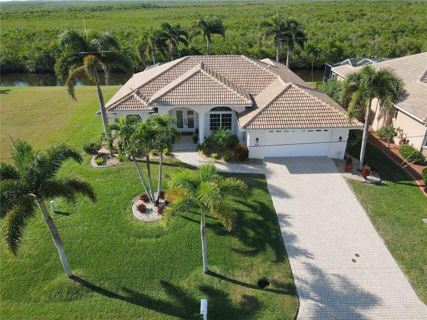Welcome to Punta Gorda and this beautiful waterfront home in Burnt Store Isles which is a golf course community where every home is either on the water or on the Twin Isles Golf and Country Club. At 2160 sq. ft. this home has it all with 3 bedrooms, 2 full baths, and a 23 x 22 oversized 2 car garage.  Then you get to the pool area that is truly special.  This pool  is oversized at 24 x 12 with an enclosed lanai and an additional sit down area under cover that measures in at 21 x 9. It has one of the most private views right behind your home as it backs up to the mangrove area that is like watching a nature habitat movie all day long.  The canal is also a path for the dolphins and manatees that frequent the neighborhood and it is just a joy to watch while you are gazing out back on a patio area that is already installed. The curb appeal of this home speaks for itself as soon you drive up and see the mature landscaping, complimented by a inviting covered front porch and a brand new roof installed in 2024. You will notice that this home sits higher than most and thus has a great flood insurance policy at $1959 a year that is assumable for the new buyer. Other very important updates include a commercial epoxy garage floor in 2024, a complete interior paint job in 2024 and all new ceiling fans and hanging light fixtures. Electrical can lighting was added in 2024.  The heated pool was completed resurfaced in 2025 and a new filter and cannister was also replaced new. The enitre home is completely tiled throughout with a textured low gloss ceramic tile that is like new. The primary bedroom walks out to the pool area and has a great view of the lanai area and canal.  A large walk in closet combines with a primary bath that has both a seperate tub,  a walk in shower and a his and her sink set up.  Hurricane rated accordion shutters are already installed around the home with 3 electric roll down shutters that cover the front door, the front dining room window and the primary bathroom window.  The location of this home is also something to consider as it is just minutes from a local Home Depot and Publix Shopping Center at the entrance of the neighborhood.  A Walmart is just minutes away and downtown Punta Gorda with all it has to show is less than 10 minutes away.  Downtown has  so many historical sites to visit along with events most weekends like Halloween, the annual Christmas Tree lighting, seafood festivals, boat shows and lets not forget a fan favorite, the Saturday morning Farmers Market!!  For all you golfing enthusiast, there is 8 different golf courses within a 20 minute drive.  So many different type of restaurants downtown from sports bars, pubs, fine dining and different cuisines to choose from.  A 4 mile long walk along the harbor is awe inspiring with a huge playground at the park on the harbor and then the most important thing is of course, PICKLEBALL courts everytwhere including the newer pickleplex that has league play and tournaments all the time.  So come and not only view this home for yourself, but go out and enjoy the downtown area and take a walk to see and read about some of our history here in Punta Gorda.