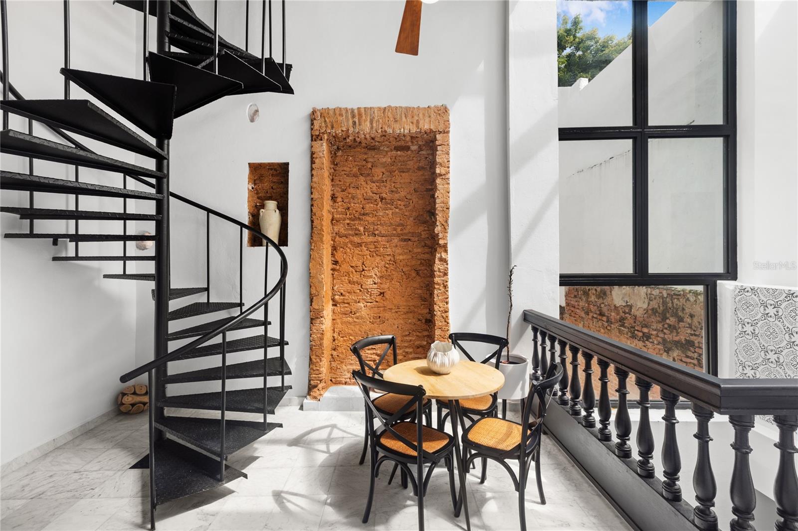 Introducing 66 Caleta Street, Old San Juan’s most coveted address.. Settled within the pristine treetops of the most historically significant strip in the oldest living city in the US.An intimate retreat steeped in history yet designed for modern living.
Originally built in 1610 and carefully restored, this 3,290-square-foot residence unfolds across two levels, blending Spanish Colonial elegance with thoughtful updates. From the moment you step inside, the scale of the space is immediately felt, with 15-foot-high ceilings and handcrafted hydraulic tiles setting a tranquil tone. The home’s 5 bedrooms and 3 bathrooms are arranged to create a natural flow between gathering spaces and private quarters, offering a quiet retreat within the energy of the city.
Designed for both entertaining and everyday living, the first floor spans 1,332 square feet, featuring a formal dining area, a chef’s kitchen, a wet bar, a breakfast nook, a guest bedroom, a full bathroom, and a cozy media room. A set of doors opens to an interiorpatio measuring 608 square feet, where an outdoor kitchen transforms meals into an alfresco experience. Upstairs, the 1,350-square-foot second level provides a more secluded sanctuary, with 4 additional bedrooms, 2 full bathrooms, and a secondary kitchenette/laundry area. A spiral staircase leads to the rooftop terrace, offering an elevated perspective of the city’s rooftops and the rhythm of life below.
The architectural integrity of this home remains intact, with original marble flooring, restored archways, and exposed wooden beams. Every room is framed by 12- to 15-foot ceilings, amplifying the sense of space and airiness. For modern convenience, the home is fully furnished and equipped with a water softening system, backup power generator, 150-gallon water cistern, and a solar water heater. Located just steps from landmarks such as Hotel El Convento, Catedral de San Juan, and the iconic Puerta de San Juan, the home sits within history yet feels like its own intimate refuge within it. A rare opportunity to own a place where the past and present co-exist in perfect harmony.