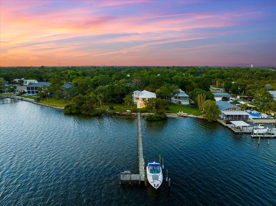 Outstanding opportunity to own this fabulous waterfront property, located directly on the Manatee River, in a blissful tropical Florida setting not easily found today. Offering sweeping water views, private deep-water dockage and impeccable craftsmanship throughout, this esteemed property, aptly named “Rio A Mar” or “River to Sea”, offers the perfect back-drop for the coastal lifestyle of your dreams. Completed in 2019, the custom-built residence embodies the unmistakable charm and elegance of famed Dutch West Indies architecture, both on the exterior and interior, telling the same story of relaxed sophistication through quietly luxurious appointments and remarkable design specifications. These features include a private Elevator, deluxe “Smart Home” capabilities, full-house natural gas generator, outdoor Summer Kitchen and a third level observation deck to name just a few. The captivating open interior living spaces exude both warmth and elegance with plenty of room to gather, dine and relax, all with stunning water views, a gorgeous gas fireplace and sliders opening to a huge expanse of covered terraces seamlessly melding the indoor and outdoor spaces for year-round enjoyment. Inset cabinetry, custom built-in’s, seamless French oak wide-plank engineered wood flooring and 10-foot tray ceilings define the home’s harmonious layout and bright airy interior. Entertain with ease in the central Chef’s Kitchen with its premium butcher block island, hidden Butler’s Pantry with coffee bar and wine cooler, double convection ovens, gas range and concealed appliance cabinetry. The adjoining Dining Room was designed to generously accommodate the largest of tables where every meal becomes a celebration of life’s best moments with friends and family. The incredible Primary Suite showcases gorgeous water views and boasts a fabulous Master Bath that pampers with a huge digitally controlled Smart Shower, free-standing soaking Tub and dual vanities. The adjacent closeted wardrobe and dressing area provides the epitome of classic luxury. Approaching the home’s entrance, a sunny courtyard welcomes to a lower entry lobby with Elevator access and a large air-conditioned Flex Space, or workshop, and two separate garages that form a motor court within the circular drive. The courtyard’s stone staircase leads up to a second-level porch entry with custom wood front door and charming wood patio doors to throw open and enjoy a delightful cross breeze. Offering the best in Florida waterfront living, this hidden gem is tucked away on a quiet street in Palmetto’s charming historic River District just minutes from downtown Bradenton and a short drive to St. Petersburg, Sarasota, Tampa and the area’s famed Gulf Beaches and prominent attractions.