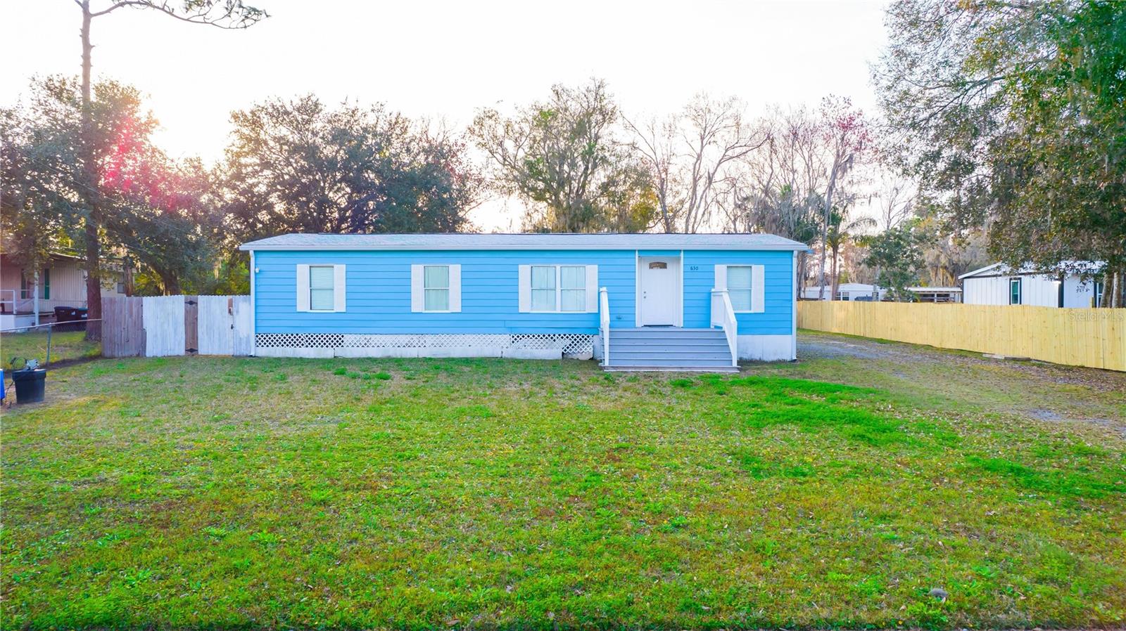 Welcome to your private retreat in East Orlando! This charming 3-bedroom, 2-bath manufactured home sits on a spacious 0.31-acre lot with no HOA, offering plenty of room to roam and the freedom to enjoy your property—bring your boat or RV! Inside, you’ll find an open-concept layout with a modern kitchen featuring granite countertops and stainless steel appliances, perfect for cooking and entertaining. The living and dining areas flow seamlessly, and each room feels bright and inviting. Recent updates add exceptional value and peace of mind, including a New Air Conditioning Unit (2022) installed by Total Cool, Master Bathroom Renovation (2022), Roof Replacement (2023), Front Balcony Repair (2023), and Water Purification System Installation (2018). The property benefits from both a well water system with full filtration and access to public water, giving you flexibility and reliability. Step outside to a large covered back deck overlooking a generous yard with mature trees for privacy, plus an exterior storage shed for added convenience. Conveniently located near local schools, with quick access to East Colonial Drive (SR 50) and SR 520 for easy commutes to downtown Orlando, UCF, beaches, shopping, dining, and parks. Outdoor enthusiasts will love the proximity to Hal Scott Regional Preserve & Park and Bithlo Community Park. With no HOA and flexible R-T-2 zoning, you have the freedom to customize the property to your needs. This home offers the perfect blend of privacy, convenience, and potential—schedule your showing today!