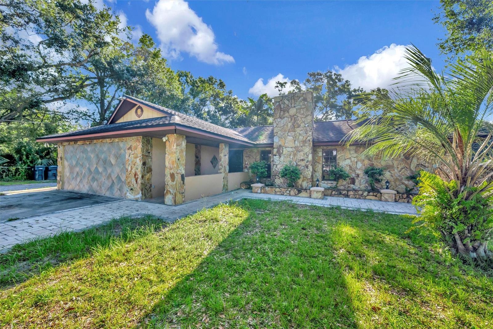 Welcome to this rare and versatile property nestled in unincorporated Hillsborough County, offering nearly an acre of land, privacy, and room to grow. The main residence is a spacious 3-bedroom, 2-bath home full of charm and function, featuring vaulted ceilings, a wood-burning fireplace, newer appliances, and plenty of natural light. A converted garage adds flexibility, ideal for an office, gym, or bonus room. One of the home's highlights is the oversized sunroom with a built-in bar, perfect for entertaining or relaxing while overlooking the expansive backyard.Privately situated behind the main home, in a separately fenced portion of the property, you'll find three seperate one-bedroom Accessory Dwelling Units(ADU)offering their own entrances, kitchens, and a shared laundry room. Two of the suites are located above a detached double garage, while the third sits just behind it. Perfect for multi-generational living, guest accommodations,or let the additional units help offset your mortgage while you enjoy the spacious, no-HOA lifestyle this unique property offers.With ample outdoor space, mature trees, and no HOA, the possibilities here are endless. Bring your vision—whether it’s gardening, RV/boat storage, home workshops, or just enjoying the extra breathing room. The detached double garage serves the main house and offers excellent storage or project space.Located in a peaceful, established area with easy access to major roads, shopping, and dining—yet far enough to enjoy privacy and serenity—this property is a true gem. Schedule your showing today and explore the potential of this one-of-a-kind property!
