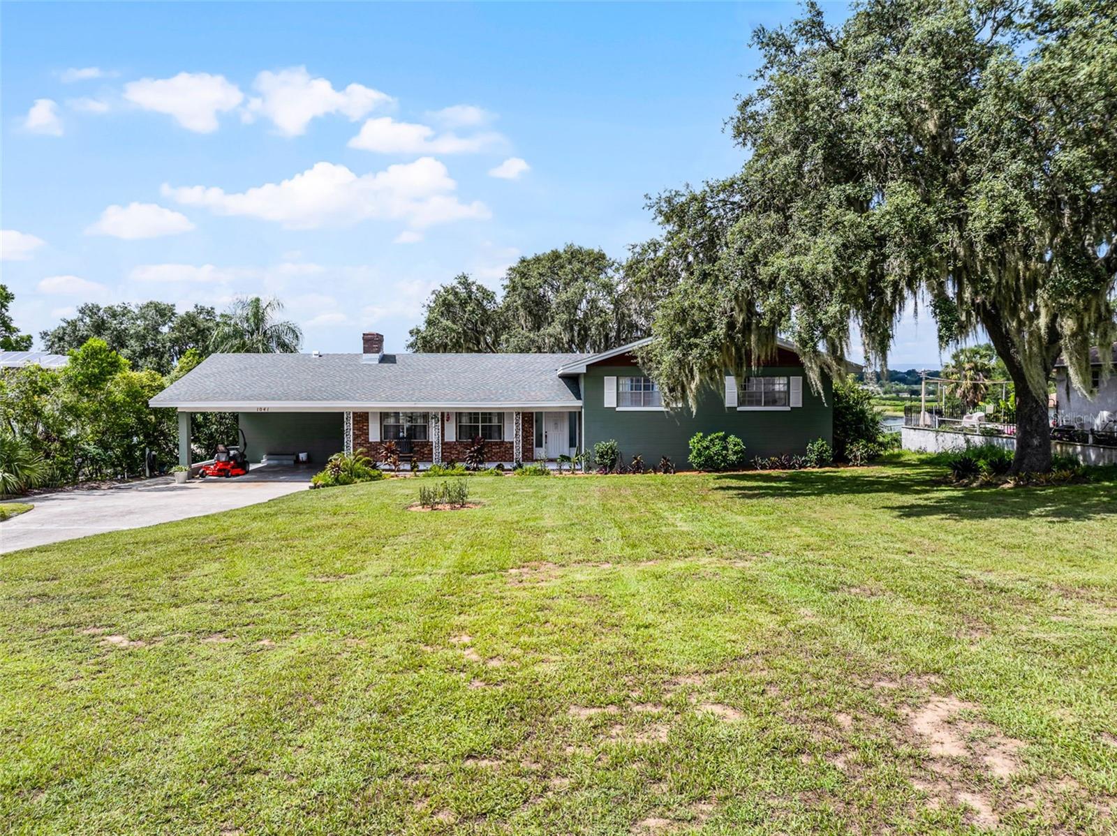 LAKE WAILES TRI-LEVEL BEAUTY! Don’t miss this incredible opportunity to enjoy lakefront living in this custom home with over 3,800 SF living area infused with many splendid traditional and modern influences throughout. Situated on a huge 100’x432’ lakefront lot, this amazing 4 BD 3½ BA home stands in a highly desirable area, known for its tranquil and convenient, central location. The conventional floor plan provides living areas on the first level, sleeping quarters and bathrooms on the second level; plus, a walk-out lower level with casual living space, storage and utility areas. The home has wonderful mill work and finishes, crown molding, wainscoting, chair rail and built-ins; stunning wood floors and handsome slate tile; and the large windows afford spectacular views of Lake Wailes. The formal living room boasts a wood-burning fireplace, and the formal dining room has picturesque lake view; both rooms link to the spacious eat-in kitchen outfitted with gas cook-top w/stainless exhaust fan, built-in ovens, farmhouse sink, travertine backsplash, granite counter tops and sliding glass doors that give a gracious flow to the screen room. Completing this first level is a den/office, a half-bath and access to the carport. The upstairs owners’ suite offers a screen balcony, walk-in closet and luxury bathroom with clawfoot soaking tub, large tile shower with bench and dual sinks. The additional bedrooms have built-in shelves w/desk, and they share a full bathroom with dual sink vanity. The walkout lower level offers a spacious room that can be used great as a family room, MIL suite, or as a fourth bedroom, it has an adjacent full bathroom, laundry room, plenty of storage area, newly wired for a small kitchenette to be added, and tucked within this lower level is a bomb shelter. New architectural shingle roof, R30 Insulation, and upstairs an energy efficient washer and dryer installed 2025. This amazing home is a short distance to the paved and lighted path around Lake Wailes, to sports fields, parks, shopping and medical facilities. Conveniently located in Central Florida and a short distance to Tampa, Orlando and coastal beaches. Call to schedule your private viewing of this well-maintained beauty!