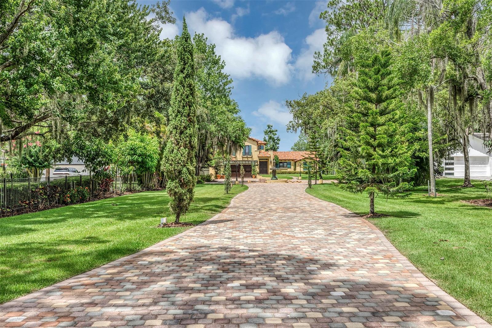 Discover this exquisite lakefront property nestled on over 1.9 acres with more than 100 feet of water frontage on LAKE TIBET and part of the Butler Chain of Lakes. This home offers breathtaking views and absolutely stunning sunsets. As you drive onto the winding paver circular driveway with lovely fountain and beautiful landscaping, you will notice the terracotta tile roof and the undeniable architectural style of this home. The 2 car garage has EV charging station. Once you enter the home you will be impressed with the whole house automation system, motorized window treatments, travertine floors, gas fireplace and crown moulding. At the heart of the home, the chef’s kitchen featuring elegant custom cabinetry, boasts of a large island, granite counter , 2 Sub Zero appliances, reverse osmosis system, pot filler, Wolf steamer, warming drawer and wine fridge. Downstairs are 2 additional bedrooms with en-suites each with special features. Upstairs, You will admire the solid hardwood flooring and attention to details. Primary suite overlooks the breath taking view of Lake Tibet and features en-suite adorned with stone flooring with stand alone tub and separate shower. The primary suite has a large walk-in closet with a custom built closet system w/safe and another separate closet. Two additional bedrooms upstairs share a full bath.
A sparkling pool w/spa within the screened patio offers a tropical escape with a summer kitchen featuring, large grill, hotplate, warming tray, pot filler and TV and misting station. The secondary covered patio outside the screened enclosure is perfect for an additional quiet oasis to enjoy your stunning views. The newly re-built dock and covered boat house w/lift (2023) with composite decking comes complete with electric & water is perfect for the enjoyable days and nights on the water. Other features include updated septic system(2024), new pool pump (2025), H2O Water Softener system, No Home Owner Association. Seller is leaving all electronics within the home. Conveniently located minutes from “Restaurant Row”, Disneys Springs, Bay Hill and zoned for “Top Rated” Schools. Schedule private tour of this remarkable home today.