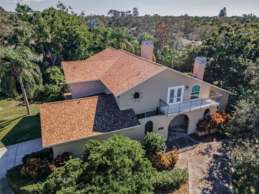 Timeless Mediterranean Revival Estate with Resort-Style Pool Oasis on Over Half an Acre in Prestigious Carlton Estates. Step into a world of enduring elegance with this captivating two-story Mediterranean style pool home, where architectural splendor meets elevated leisure and family-friendly luxury. Nestled on more than half an acre in one of Pinellas County’s most sought-after enclaves, this exceptional residence offers over 3,800 square feet of exquisitely designed living space. Inside, authentic character abounds, from rich Saltillo tile floors and arched doorways to bay windows, wrought iron railings, and soaring beamed ceilings that crown the interiors with timeless charm. A brand-new roof and updated windows and doors throughout ensure peace of mind and modern comfort. From the moment you enter, bold Tuscan-style tile flooring sets a tone of European permanence. The main level unfolds with expansive, interconnected living spaces, including a formal living and dining room that exudes warmth and sophistication—perfect for elegant entertaining or intimate evenings. At the heart of the home lies a grand, light-filled family room, where two-story vaulted ceilings and exposed wood beams evoke the rustic romance of a Spanish mission. Anchoring the space is a striking wood-burning fireplace, casting a cozy glow across gatherings large or small. The adjacent chef’s kitchen is a seamless extension of the living space, featuring a central island and open sightlines that keep the cook connected to the conversation. A sunlit breakfast nook with a bay window offers the ideal setting for casual meals and morning coffee with a view. Thoughtfully designed for flexibility, the main floor also includes a secluded office retreat with a beamed ceiling and a generously sized bedroom with an adjacent full bath—perfect for guests, multigenerational living, or a private sanctuary. A sweeping staircase of wood and wrought iron leads to the upper level, where three generously sized bedrooms and a sunlit, multi-purpose bonus room span the second floor. The expansive primary suite is a true retreat, complete with a dramatic stone fireplace and a private veranda for quiet moments under the stars. Outdoors, the Mediterranean lifestyle comes to life. A sprawling covered lanai with paver flooring and elegant arched breezeways opens to a park-like backyard, where mature landscaping surrounds a large, sparkling inground pool. Whether hosting alfresco soirées or enjoying tranquil afternoons in the sun, this outdoor oasis is designed for seamless indoor-outdoor living. This is more than a home, it’s a statement of style, serenity, and sophistication. With four bedrooms, 4 baths, a resort-style backyard & pool, and over half an acre in one of Pinellas County’s finest neighborhoods, this home checks every box. Don’t miss your chance to experience the elegance and ease of Carlton Estates living! Experience the European charm and refined design for yourself.