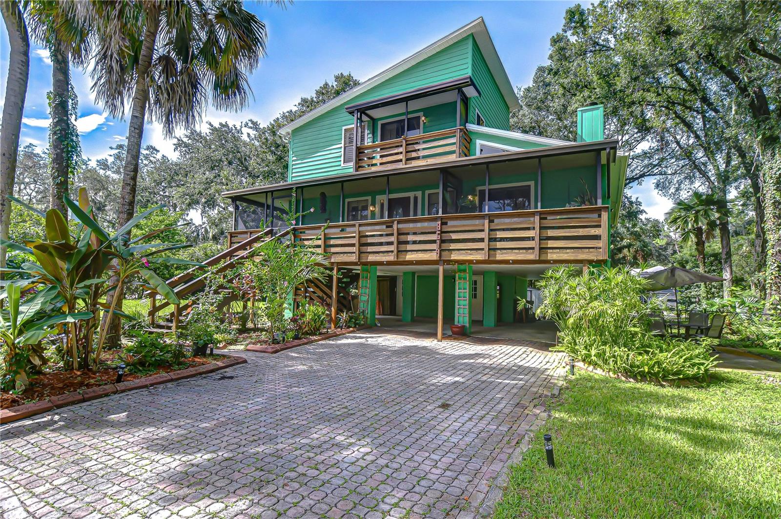 Set on a beautifully landscaped .32-acre lot, this 3-bedroom, 2.5-bath residence offers 2,328 sq. ft. of thoughtfully designed living space. Built in 1984 with timeless craftsmanship, the home makes a striking first impression with its vibrant exterior, 4-car carport, and an inviting wraparound screened porch that extends your living space outdoors. Inside, soaring wood-clad ceilings, skylights, and walls of windows create a bright and welcoming atmosphere. The main living room showcases a dramatic stone fireplace, while the adjacent dining area captures treetop views through expansive glass. At the heart of the home, the kitchen blends warmth and functionality with a tray ceiling enhanced by wood and recessed lighting, granite countertops, and abundant workspace. A built-in double oven and premium appliances make cooking a breeze, while glass cabinet inserts provide a touch of elegance. The contrasting center island features a sleek cooktop beneath modern pendant lighting, creating a perfect spot for gathering. A large window over the sink frames views of the lush backyard, filling the space with natural light. Upstairs, the primary suite is a retreat with its own sitting area, gleaming wood flooring, and a custom walk-in closet with built-ins. The spa-inspired bath includes a jetted tub and pedestal sink. A second bedroom functions as a private suite with an ensuite bath and balcony access, making it perfect for guests or multi-generational living. The lower level provides two versatile bonus rooms, abundant storage, and access to the oversized fenced backyard shaded by mature trees—an ideal space for entertaining or quiet relaxation. Recent improvements include a newer AC system (2021), updated blinds, rebuilt exterior stairs, and a fully screened patio.
All this, just minutes from I-75, shopping, dining, golf, and recreation—this rare find blends character, comfort, and convenience in one unforgettable package. Arrange your showing now!