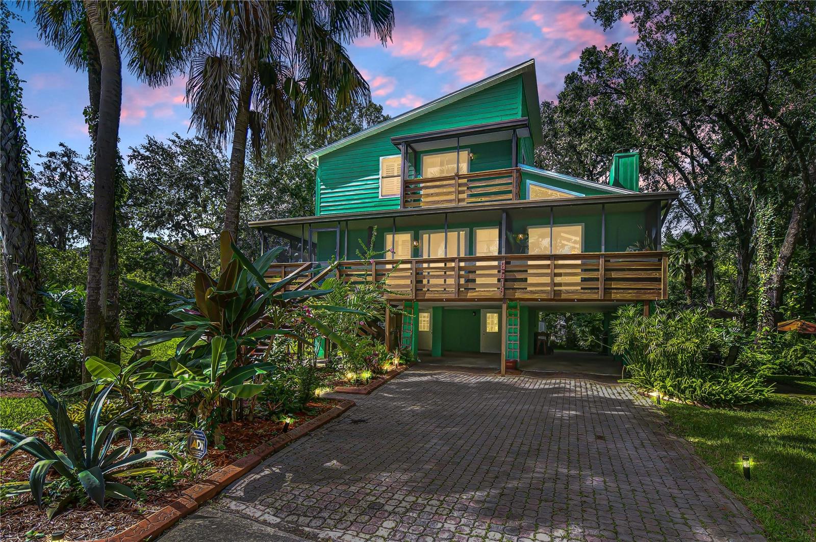 Set on a beautifully landscaped .32-acre lot, this 3-bedroom, 2.5-bath residence offers 2,328 sq. ft. of thoughtfully designed living space. Built in 1984 with timeless craftsmanship, the home makes a striking first impression with its vibrant exterior, 4-car carport, and an inviting wraparound screened porch that extends your living space outdoors. Inside, soaring wood-clad ceilings, skylights, and walls of windows create a bright and welcoming atmosphere. The main living room showcases a dramatic stone fireplace, while the adjacent dining area captures treetop views through expansive glass. At the heart of the home, the kitchen blends warmth and functionality with a tray ceiling enhanced by wood and recessed lighting, granite countertops, and abundant workspace. A built-in double oven and premium appliances make cooking a breeze, while glass cabinet inserts provide a touch of elegance. The contrasting center island features a sleek cooktop beneath modern pendant lighting, creating a perfect spot for gathering. A large window over the sink frames views of the lush backyard, filling the space with natural light. Upstairs, the primary suite is a retreat with its own sitting area, gleaming wood flooring, and a custom walk-in closet with built-ins. The spa-inspired bath includes a jetted tub and pedestal sink. A second bedroom functions as a private suite with an ensuite bath and balcony access, making it perfect for guests or multi-generational living. The lower level provides two versatile bonus rooms, abundant storage, and access to the oversized fenced backyard shaded by mature trees—an ideal space for entertaining or quiet relaxation. Recent improvements include a newer AC system (2021), updated blinds, rebuilt exterior stairs, and a fully screened patio.
All this, just minutes from I-75, shopping, dining, golf, and recreation—this rare find blends character, comfort, and convenience in one unforgettable package. Arrange your showing now!