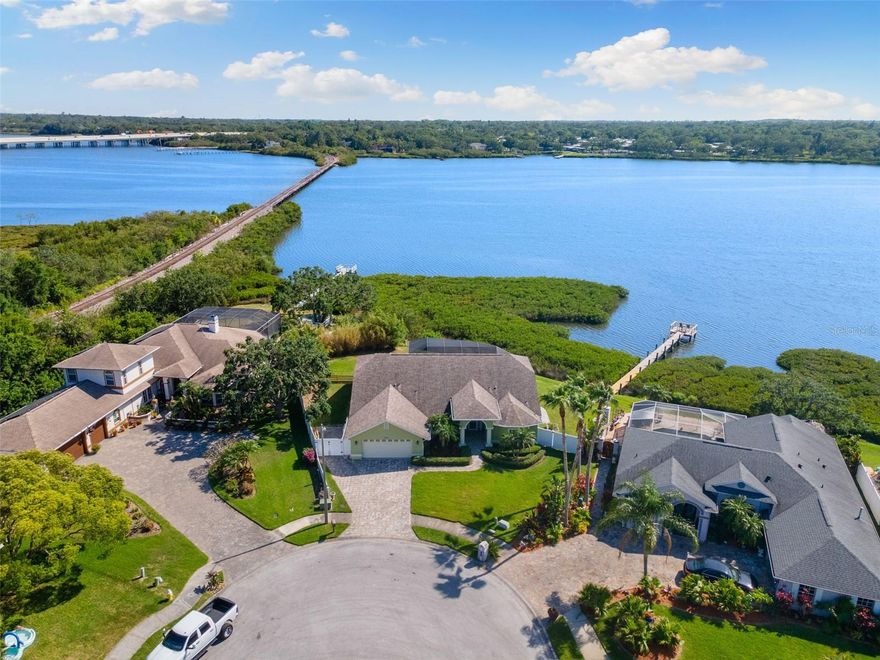 Significant Price Adjustment – Waterfront Beauty in Coveted East Lake Corridor – The Best Lot in this highly desired Community! Motivated Sellers!  Coastal Elegance on Upper Tampa Bay — this private waterfront retreat is back on the market and ready to impress. Set on the premier lot in the community, the home offers 165 feet of unobstructed bay frontage, unmatched privacy, and direct open-water access, creating a lifestyle that blends luxury, natural beauty, and peace of mind. Elevated nearly ten feet above the waterline on a lush .36-acre lot, the fully remodeled three-bedroom, two-bath residence showcases high-end craftsmanship throughout, with vaulted ceilings, crown molding, and a sun-drenched open-concept design finished with wood-look ceramic tile.  The gourmet kitchen is a chef’s dream, featuring GE Profile appliances, a gas range, a grand island with seating, pendant lighting, and abundant custom cabinetry. The spacious primary suite offers two walk-in closets, soaring ceilings, and sliding doors that open directly to a resort-style outdoor living space. Here, a self-cleaning saltwater pool, expansive paver deck, and covered lanai with a built-in outdoor kitchen make entertaining effortless while offering front-row views of the bay.  Outdoors, a private dock with a mechanical kayak and paddleboard launch makes it easy to fish, paddle, or simply relax as dolphins and manatees swim by at sunset. This home has been hurricane-hardened with impact-rated windows, doors, and garage door, reducing insurance costs and providing peace of mind. Additional upgrades include a Trane high-efficiency WiFi Smart HVAC system still under warranty, a tankless water heater, Ring security, programmable sprinklers, smart-home integration, and controlled pool jets and lighting. A gated six-foot parking pad provides space for a boat or jet skis, while the oversized two-car garage offers built-in cabinetry and overhead storage.  Nestled in a quiet, no-through-traffic enclave and steps from Sheffield Park with tennis courts, trails, and dog parks, this home is also just minutes from A-rated schools, Tampa, St. Pete, airports, shopping, and world-class beaches. With its unbeatable location, premium lot, and new price, this is a rare opportunity to fall in love with the Florida coastal lifestyle. High and dry through recent storms, this property offers confidence as well as charm.**Ask us about our Preferred Lender Incentive available where you could save thousands $$$**