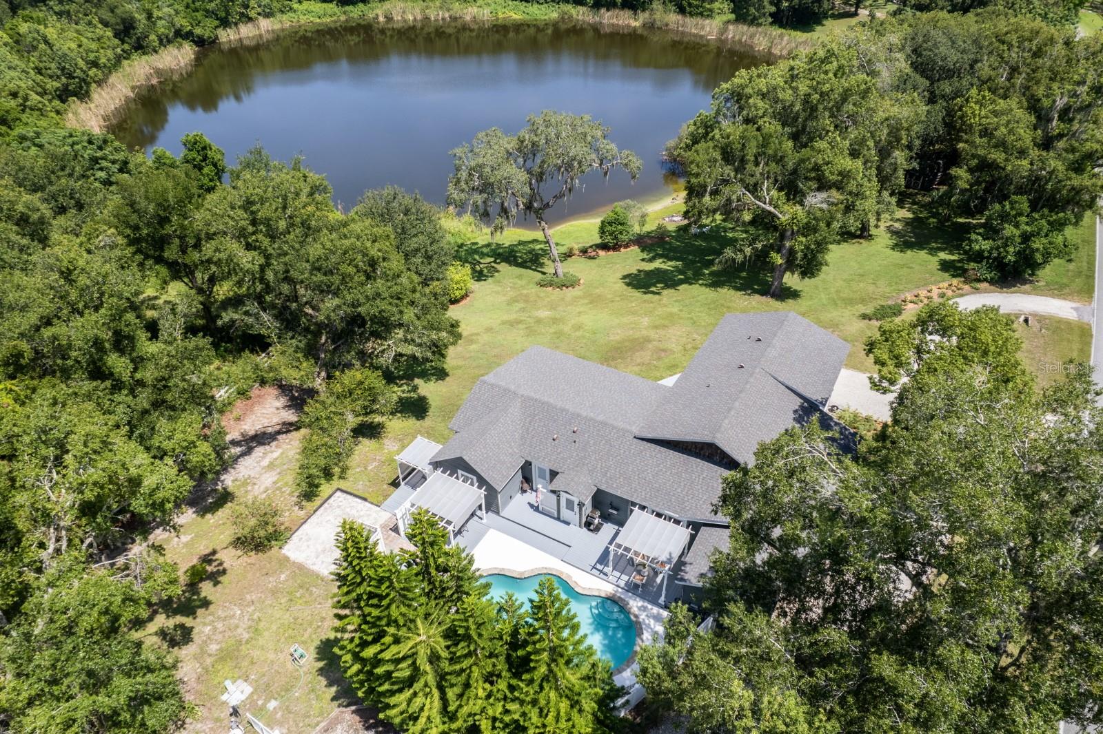 Welcome to your peaceful lakefront escape on Lake Lizzy! This stunning 4-bedroom, 3-bath Craftsman-style home is nestled on 3.53 private acres, offering elevated lake views, ultimate privacy, and room to roam. Thoughtfully designed, the home allows for main-level entry in the front while the back provides beautiful views overlooking the lake from a higher elevation, creating a truly special setting. Step inside to find double-pane windows throughout and a new roof installed in 2022, offering comfort and energy efficiency year-round. The kitchen is an entertainer’s dream, featuring granite countertops, soft-close cabinetry, pull-out drawers, and a walk-in pantry room for extra storage. The open floor plan flows seamlessly into both the formal living room and spacious family room, each with its own electric fireplace, perfect for cozy evenings or hosting gatherings. The primary suite offers stunning lake views, along with a spa-like bath that includes a soaking tub and tiled walk-in shower. Step outside to your private oasis featuring a rock-edged pool, hot tub positioned to overlook the water, and an outdoor shower for added convenience. On the opposite side of the home, a large front porch invites you to relax and enjoy the peaceful surroundings. Additional features include a two-car garage with a workshop area, perfect for hobbies, and a basement that provides ample space for all your storage needs. The layout also offers flexible living space that could easily function as a mother-in-law suite for those needing separate accommodations. Whether indoors or out, this home offers comfort, space, and a unique lakefront lifestyle—plus frequent visits from deer, birds, and other wildlife that make it a true nature lover’s retreat.