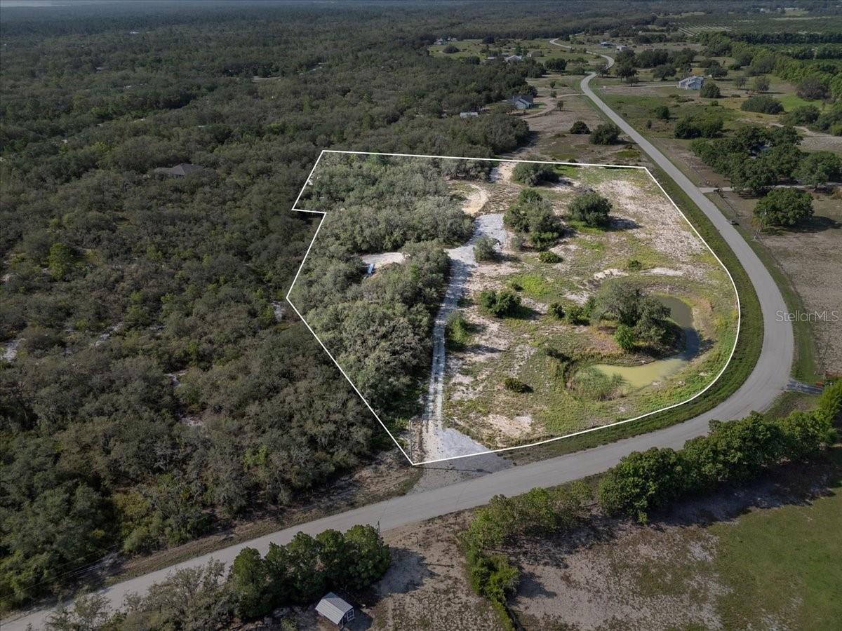 Expansive 7.59-Acre Homesite Package in Gated Wildlife Sanctuary...Introducing a rare opportunity to own two high-and-dry parcels in the gated, wildlife-designated community of Blue Jordan Forest in scenic Frostproof, Florida. This combined 7.59-acre offering includes a 4.49-acre lot (1867 Old Grove Trail) and a 3.10-acre lot (1943 Old Grove Trail), providing the ideal setting for your custom estate or multi-generational compound surrounded by peace, privacy, and the beauty of nature. A professionally installed aggregate driveway spans approximately 1,200 feet, offering easy access across both parcels. The property is fully fenced with a private gated entry and features a serene pond that enhances the natural charm of the landscape. Elevated building sites provide panoramic wooded views, incredible sunsets, and ample space for designing your dream home. Community zoning allows for single-family construction only (no mobile homes on these lots), with a minimum of 1,000 square feet for single-story homes and 1,500 for two-story residences. For more information on community guidelines, visit bluejordanforest.com. Blue Jordan Forest is a unique conservation-minded neighborhood where residents enjoy the quiet simplicity of Old Florida living. Deer, foxes, bald eagles, and native birds thrive here, making every day feel like a retreat. With an average of 3 acres per homesite, the community offers rare seclusion while remaining just a short drive from Lake Wales and surrounding amenities. Enjoy the freedom to live your rural dream—ride ATVs, golf carts, have the garden of your dreams, and explore scenic forest trails. The low annual HOA fee covers road maintenance, refuse collection, lighting, and gated security, all supported by an active and involved ownership association. Beyond the gates, discover Frostproof—nestled between Lake Clinch and Lake Reedy—a friendly, small town known for its charming downtown and relaxed pace of life. Outdoor lovers will appreciate nearby Lake Wales Ridge State Forest, featuring rare plant species and scenic trails like the Scrub Jay Loop. For hunters, anglers, and campers, the nearby Walk-In-The-Water Wildlife Management Area offers over 6,000 acres of preserved land for primitive camping, hiking, and seasonal recreation. If you're seeking a private, spacious, and peaceful lifestyle in a one-of-a-kind natural setting, this exceptional land package in Blue Jordan Forest is your opportunity. Schedule your private tour today and experience what makes this community so special.