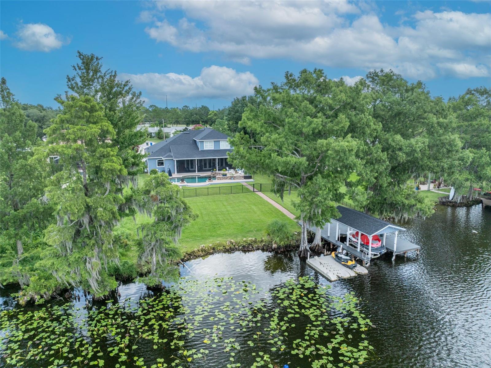 Under contract-accepting backup offers. Exquisite Lakefront Estate on Skiable Long Lake!
Welcome to your personal lakefront paradise in Oviedo, nestled along 100 feet of shoreline on spring-fed, 70-acre Long Lake—a private, skiable lake perfect for boating, paddleboarding, and sunset cruises. This stunning property comes fully equipped with a boat and jet ski, offering immediate access to the lake lifestyle. With 200 feet of backyard depth, a covered boathouse with lift, and expansive green space, you’ll enjoy unforgettable Florida sunsets from your own backyard retreat.
The resort-style pool features a sunshelf and playful fountains, setting the scene for both daytime fun and nighttime ambiance. Surrounding it, the back porch is designed for effortless outdoor living, complete with a pool bath, retractable screens, and a grilling area—ideal for entertaining or unwinding after a day on the water. Fire pots and a lakeside fire pit add a dramatic touch to evening gatherings.
Step inside to discover a home designed for both elegance and everyday ease. The expansive layout offers 5 bedrooms, 4 full baths, and 2 half baths, plus double-paned windows that fill each room with natural light and hand-scraped hardwood floors that add warmth and richness. The chef’s kitchen is a standout with a gas cooktop and pot filler, copper farmhouse sink, double convection ovens, built-in microwave, and oversized refrigerator—all flowing into a grand family room anchored by a custom stone fireplace.
The first-floor master suite features two large walk-in closets and a spa-like bath with a stone floor and dual-head shower. A private guest suite is also located on the main level. Upstairs, a split staircase leads to two separate wings, ideal for multi-generational living or extended guest stays. One wing includes a bonus/media room, as well as a spacious bedroom and workout/flex space room.
With over $250,000 in recent upgrades, this home offers both luxury and peace of mind—including a whole-house security system with integrated cameras, a custom office with built-in desk and shelving, a new roof (2022) on the home, a dock with new roof and lighting, whole house Kintico water softener, kitchen reverse osmosis system and an oversized 2 car garage with epoxy floors and overhead storage.
Located in a peaceful, upscale enclave with top-rated Seminole County schools, this lakefront estate delivers an unmatched blend of natural beauty, thoughtful design, and everyday comfort. *list of recent updates available upon request