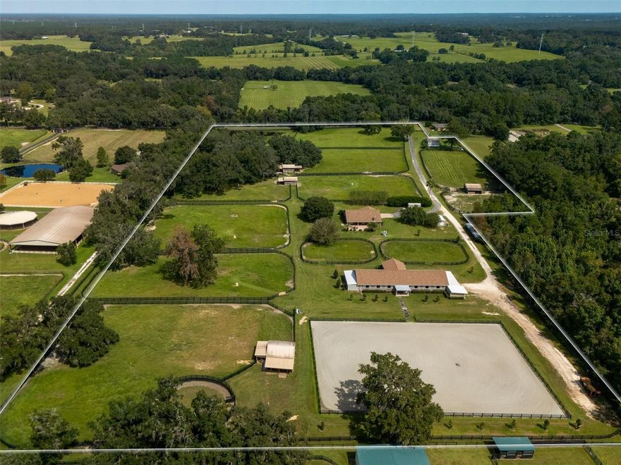 This fully fenced 19+ acre farm in Reddick is less than 20 minutes from the World Equestrian Center and combines established equestrian facilities with comfortable living in a peaceful setting. Shaded by mature oaks, the property is thoughtfully laid out with 11 lush paddocks, a 12-stall center-aisle main barn, and an additional 12 stalls in separate run-in sheds. The main barn is a standout, featuring a well-appointed barn apartment with a full kitchen, bathroom, office, tack and feed rooms, a fly spray system, and hot-water wash racks—providing everything needed for daily operations or visiting guests. Just steps away from the barn, riders will find a Longwood arena and a round pen, perfectly suited for training and exercise throughout the year. This property also includes both a 3-bedroom, 2-bath main residence and a 3 bedroom, 2-bath mobile home. The main home is bright and welcoming, with ceramic tile floors, high ceilings, and an abundance of natural light. The kitchen offers generous cabinet space and serves as the heart of the home, opening to the living areas highlighted by a charming fireplace. French doors lead to a spacious back porch, ideal for gatherings or simply enjoying serene views of the farm. For added convenience, an invisible fence is installed around the home for dogs, making the outdoor spaces safe and functional for pets. Blending function and comfort, this Reddick property offers an excellent opportunity for private enjoyment or a professional equestrian venture, in a highly desirable location.