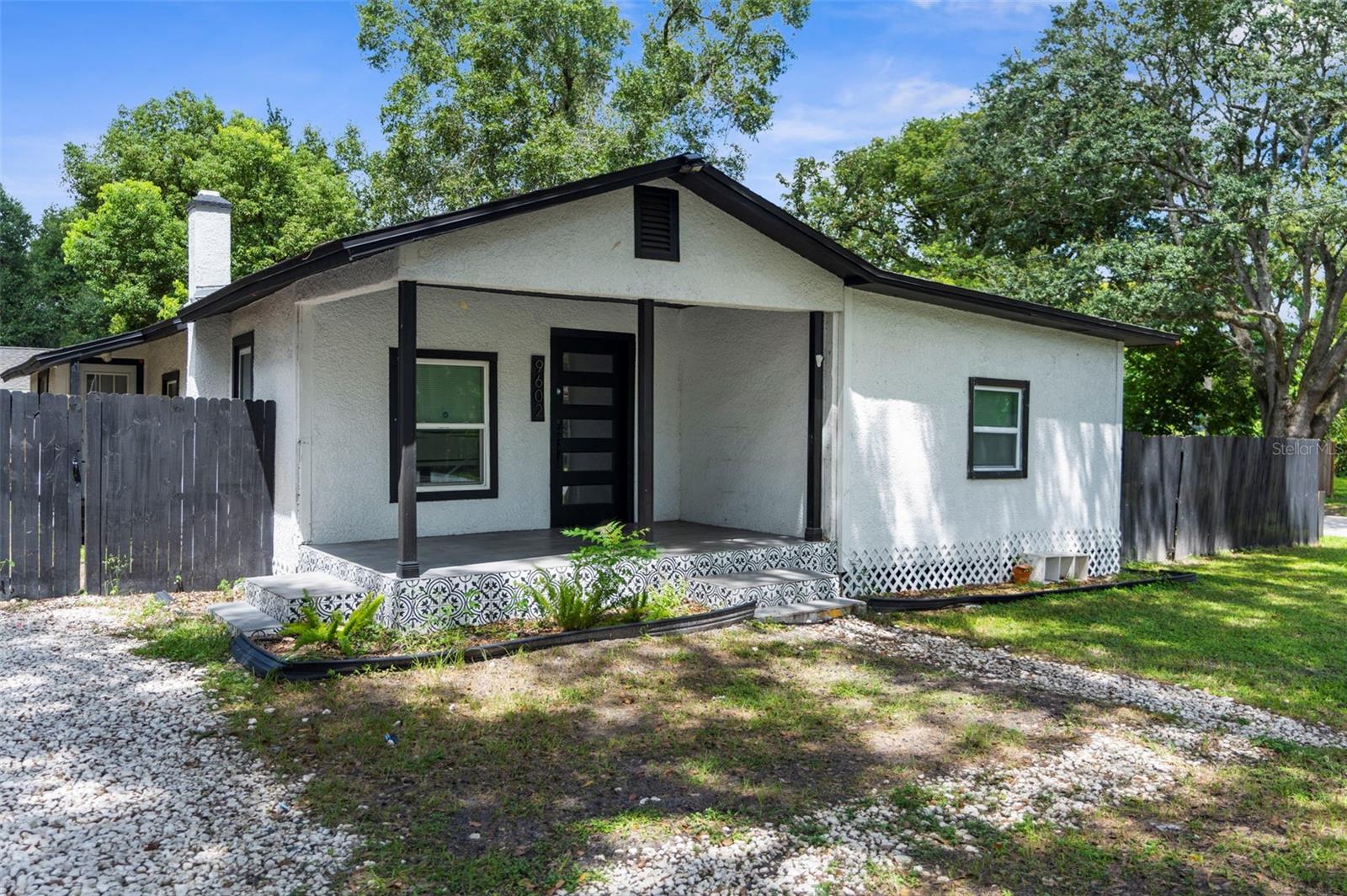 One or more photo(s) has been virtually staged. Welcome to this BEAUTIFULLY FULLY updated 3-bedroom, 1-bathroom RANCH-STYLE home, perfectly situated on a landscaped, private, and fully fenced lot (70 x 100). Built in 1934, this charming CORNER UNIT has been restored and renovated while retaining its timeless character. The home offers 1,106 sq. ft. of living space with an additional total building area of 1,254 sq. ft., all on one level. Step inside to find BRAND NEW LUXURY ENGINEERED VINYL PLANK FLOORING that’s both stylish and low maintenance—perfect for keeping the home ALLERGY-FREE. The OPEN FLOOR PLAN seamlessly connects the LIVING ROOM and DINING ROOM creating an ideal space for gathering. The kitchen is a true showstopper, featuring CALACATTA QUARTZ COUNTERTOPS with a dramatic WATERFALL EDGE BAR, NEW WHITE CABINETRY, and STAINLESS STEEL APPLIANCES. A large kitchen window over the sink allows natural light to flood the space, while a TOUCH-LESS FAUCET adds modern convenience. Stylish ARTISTIC TILE runs from counter to ceiling as a backsplash, elevating the design. The kitchen also features a SLIDING BARN DOOR that leads to the laundry room and back entrance. The home’s single bathroom is spacious and finished with FLOOR-TO-CEILING TILE, a SHOWER NICHE WITH ACCENT TILE, a WATERFALL SHOWER HEAD, and a modern LED-LIT VANITY MIRROR with adjustable lighting options. All three bedrooms are located on the main floor. The PRIMARY BEDROOM (15 X 12) stands out with an eye-catching WOOD-TRIMMED ACCENT WALL, easily accommodating a king-size bed with room to spare. A second SLIDING BARN DOOR adds character and privacy. The other two bedrooms (12 x 10 and 11 x 8) offer flexibility for guests, a home office, or family use. Outside, enjoy the FULLY FENCED BACKYARD! The south-facing front provides abundant natural light throughout the day, and the LANDSCAPED LOT sits on a PAVED STREET.Major system updates include a 2017 HVAC, 2017 ELECTRIC WATER HEATER, 2022 ROOF, and 2022 ELECTRICAL PANEL, giving you peace of mind for years to come. This prime location puts you just minutes from everything! You’re approximately 5 MINUTES FROM I-275, 10 MINUTES OR LESS TO BUSCH GARDENS, ADVENTURE ISLAND, LOWRY PARK ZOO, AND USF, and 15 MINUTES OR LESS TO DOWNTOWN TAMPA, ARMATURE WORKS, SPARKMAN WHARF, AND HISTORIC YBOR CITY. TAMPA INTERNATIONAL AIRPORT AND RAYMOND JAMES STADIUM are about 20 minutes away, and you’re just 45 MINUTES FROM AWARD-WINNING CLEARWATER BEACH.