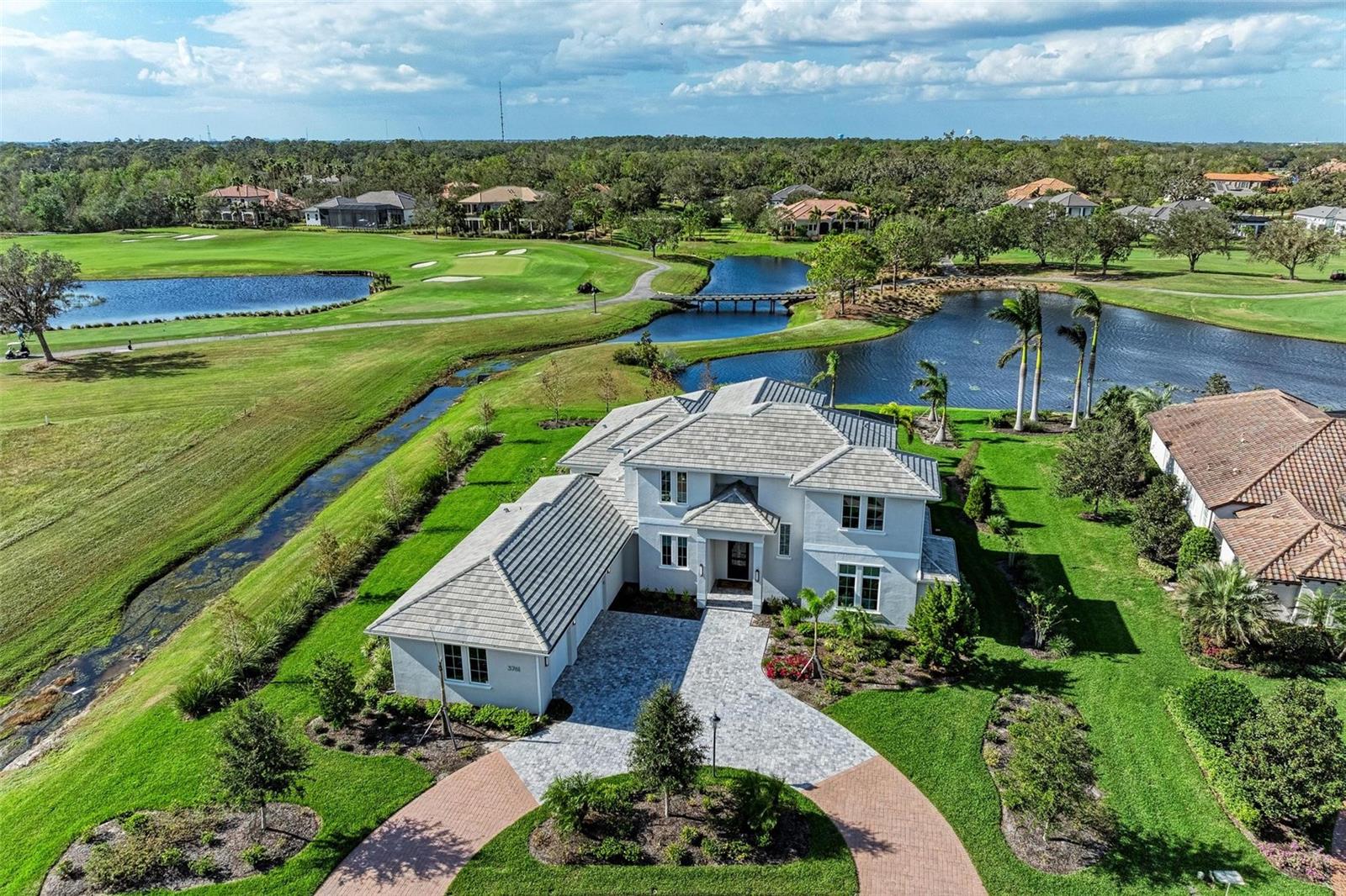 Stunning lake and golf course views are the backdrop for this contemporary custom estate in the acclaimed Founders Club. Completed in 2023 by John Cannon, this masterpiece offers superb construction quality and peace of mind. The 5-bedroom, 5-bath + bonus room + office home was lovingly designed for today’s lifestyle. Grand gathering areas transition seamlessly to incredible casual outdoor living spaces. Built of concrete block on the first and second stories, this energy efficient estate has video security, impact windows/sliders, a whole home generator, water filtration, and 5-zone heating/cooling system. Soaring tray ceilings add an airy ambiance, and 10’ pocketing sliders frame heavenly views. The first level features the private owner’s suite, a King guest-suite, an executive office with built-ins that connects to an outdoor terrace, and a large room that opens to a dreamy lanai. The striking gourmet kitchen was thoughtfully designed by a chef to be functional and beautiful. State-of-the-art appliances, an insta-hot tap, natural polished granite counters and timeless white double-stacked cabinets with an extended butler’s area will delight the most discerning. A hidden pantry offers storage. The professional-grade Dacor range has simmer capabilities and oversize burners. The massive Dacor refrigerator/freezer is a combined 54” wide. The wine cellar is temperature/humidity controlled and tailor-made for wine enthusiasts. The heart redwood racking and a separate cooling system make ideal storage of your 600 bottles. Luxurious features include designer lighting, custom window treatments, solid-core doors, classic engineered hardwood flooring in main areas and all bedrooms, Albrecht custom cabinets throughout, custom closets in all bedrooms, and an elegant designer marble feature wall in the great room. The owner’s retreat is a sanctuary with tray ceilings, serene views, outdoor access, two sizable dressing rooms and a spa inspired bath with walk-in shower, floating tub, and split vanities. The spacious downstairs laundry/utility room offers plentiful pullout drying racks, a large sink, and a second refrigerator. Upstairs is the ideal guest space for privacy with a sunlit living area and balcony with dramatic views, a built-in wet bar, two King guest suites with ensuite bathrooms and a second laundry room. The outdoor living is an oasis with two covered lanais, a heated sparkling saltwater pool/spa, vented outdoor kitchen, and clear-view screen. Landscape lighting enhances the home in the evening. This is a rare opportunity to own a custom estate without the multi-year wait on one of the most magnificent homesites in the neighborhood. Priced below today’s reproduction cost. New designer furnishings available separately, if desired. The Founders Club is a beautiful low-density 24/7 guard-gated community with over 700 acres of wetlands and preserve and only 262 homes. The renowned Robert Trent Jones Jr. golf course offers members easy tee times and is one of the only walkable courses in the region. Har-Tru tennis courts, a picnic pavilion, and playground, basketball court, and fitness center are also on site. Residents enjoy easy access to the cultural venues of downtown Sarasota and attractions of Lakewood Ranch. Optional golf/social memberships. Members enjoy a 24/7 fitness facility, stately clubhouse, community events, and a restaurant with picturesque veranda. Come see this exceptional home and discover an extraordinary lifestyle.