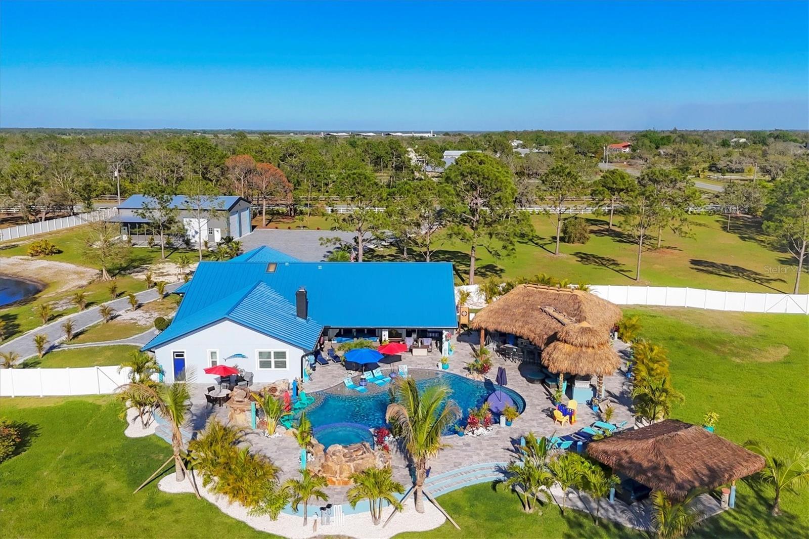Welcome to the newest finished product! This property will impress the most discerning buyers. A million dollar plus renovation has just been completed at this amazing Estate. Located only 30 minutes from Downtown Sarasota, this premier 5 Acre parcel sits on the highest elevation at nearly 99' above, soaring over all of the neighborhoods within miles. This lot is high and dry with no wetlands and no HOA, and has a large front and rear yard. 2025 Custom standing seam Metal roof, 2024 Hurricane Impact windows and Sliders, 2024 Insulated Metal Building that is 2,200 sq ft with 4 Custom 14x14 roll up doors and 1 12x12 roll up door, with RV and Motorhome hook ups. This fully fenced and Gated property offers buyers many options for Florida living. A New Construction paver driveway was just completed with over 17,000 sq ft of parking. Newly completed in 2025 a complete back yard transformation includes a private jungle firepit area, a huge elevated custom lagoon pool with 3 Natural Rock waterfalls, multiple sun shelves for lounging, a custom in water sitting table with stools, a 25 person heated spa, custom commercial outdoor kitchen with all the appliances including a hibachi grill, gas grill, wine fridge, side burner, ice stations and fridge. There is a Sunset tiki, outdoor shower, and multiple lounging areas. The backyard has been meticulously designed for entertaining and to capture the incredible sunsets, to include a lounging sunset tiki, as the back yard faces due West. A complete interior re design was completed in 2024, to include newly expanded 12' custom ceilings, a large open floor plan, custom interior wet bar, designer kitchen with double island and top of the line appliances and imported Brazilian Marble countertops.
There is too much to mention, please reach out to the listing agent for all property details.