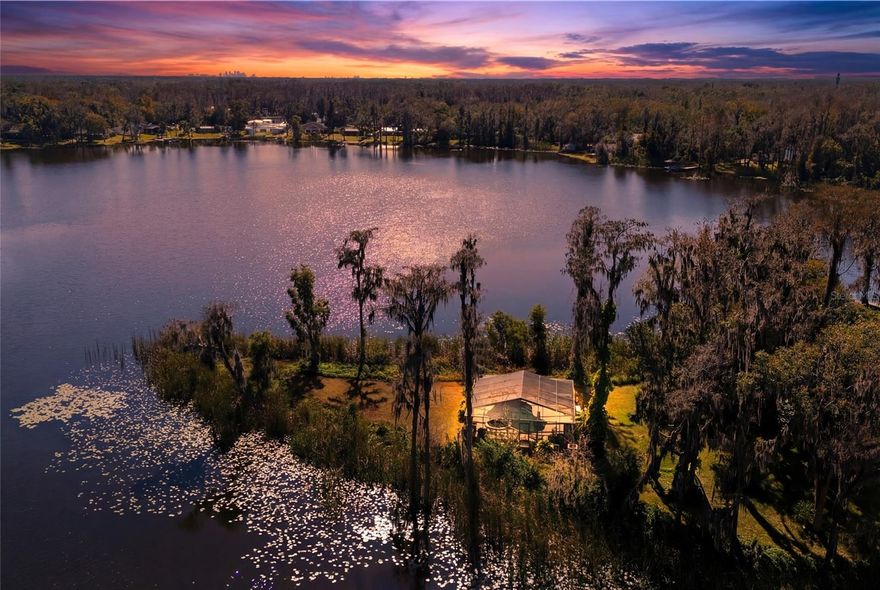 Welcome to 602 Druid Way, a private, lakefront estate tucked away on 2.63 acres in the heart of Lutz. With six bedrooms, five baths and over 4,500 square feet, this architecturally distinctive home offers total privacy and 125 feet of lake frontage ideal for water sports and peaceful sunset views. Beyond the private gate, you'll find a fully upgraded interior blending rustic charm with modern luxury. The gourmet kitchen features a stunning skylight, custom cabinetry and new Bosch appliances. Entertain with ease in the formal living and dining rooms or relax fireside in the spacious family room, complete with a brick wood-burning fireplace. The split floor plan includes upstairs primary suites with balconies that offer breathtaking views of the lake and moss-draped trees. Go outside and immerse yourself in a Florida paradise. The oversized screened lanai encloses a sparkling pool and spa, creating a tranquil retreat just steps from the water’s edge. Enjoy year-round outdoor dining, morning coffee by the lake or evenings under the stars. The unique lot shape ensures enhanced privacy, with lush lawns, mature landscaping, and plenty of space for recreational activities, gardening or simply enjoying nature. With no HOA and a setting that feels like a private resort, this is the ultimate lakeside lifestyle.