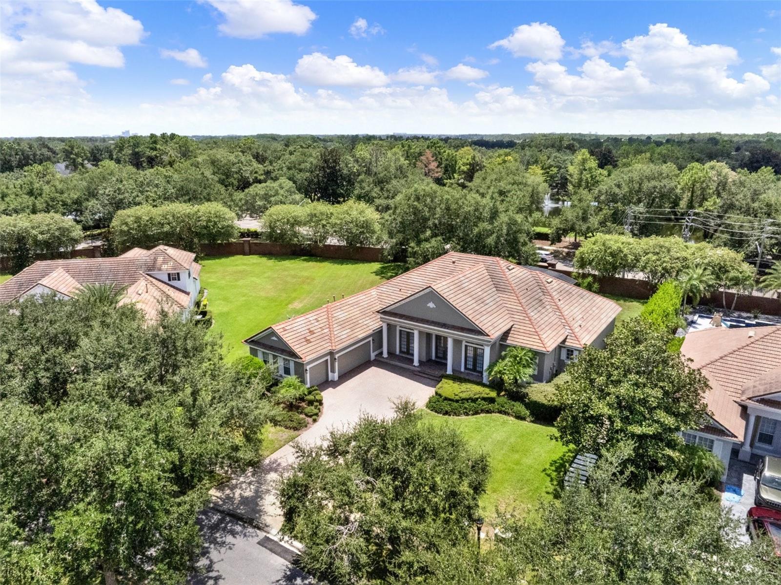 Tucked away in the prestigious guard-gated community of The Reserve at Lake Butler Sound, this exceptional 4-bedroom, 3.5-bath single-story pool home blends timeless Mediterranean style with modern sophistication. Set on over half an acre in a quiet cul-de-sac, the home welcomes you with a paver driveway, lush mature landscaping, and an elegant entry framed by architectural columns.
As you enter through the grand beveled glass French doors, you’re immediately greeted by soaring cathedral ceilings and sweeping views through the family room to the screened pool and spa beyond. The formal living and dining areas feature stately archways, tray ceilings, and designer lighting, creating a refined space for entertaining.
The heart of the home is the gourmet kitchen, designed with the chef in mind. Outfitted with granite countertops, a large breakfast bar, and a sunny dinette space, it flows effortlessly into the family room where a natural gas fireplace and rich wood floors add warmth and charm.
The spacious Owners Suite is tucked away for privacy, offering a tranquil retreat with travertine flooring, dual walk-in closets, a luxurious ensuite bath with double vanities, a large walk-in shower with dual heads, and a built-in wet bar. A flexible sitting area just outside the suite can serve as a home office, reading nook, or nursery.
Bedrooms two, three, and four offer generous space and privacy, including a jack-and-jill bath and an additional full hallway bath. A dedicated office near the front of the home can easily serve as a fifth bedroom if needed. Additional highlights include a powder room, oversized laundry room, and a 3-car courtyard-style garage.
Unwind on the ceramic-tiled pool deck surrounded by tranquil landscaping and dramatic lighting, offering a peaceful backdrop for evenings outdoors. Residents enjoy exclusive access to a community fishing pier on Lake Butler and a charming garden park, all just minutes from top-rated public and private schools, downtown Windermere, major roadways, Disney, and upscale shopping and dining.